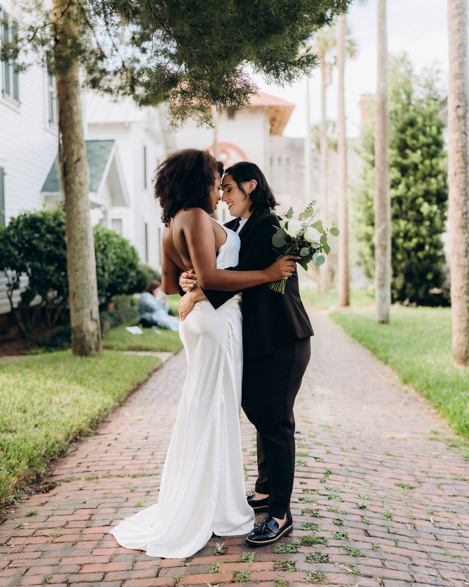Wedding couple sharing intimate moments on a brick walkway surrounded by palm trees.