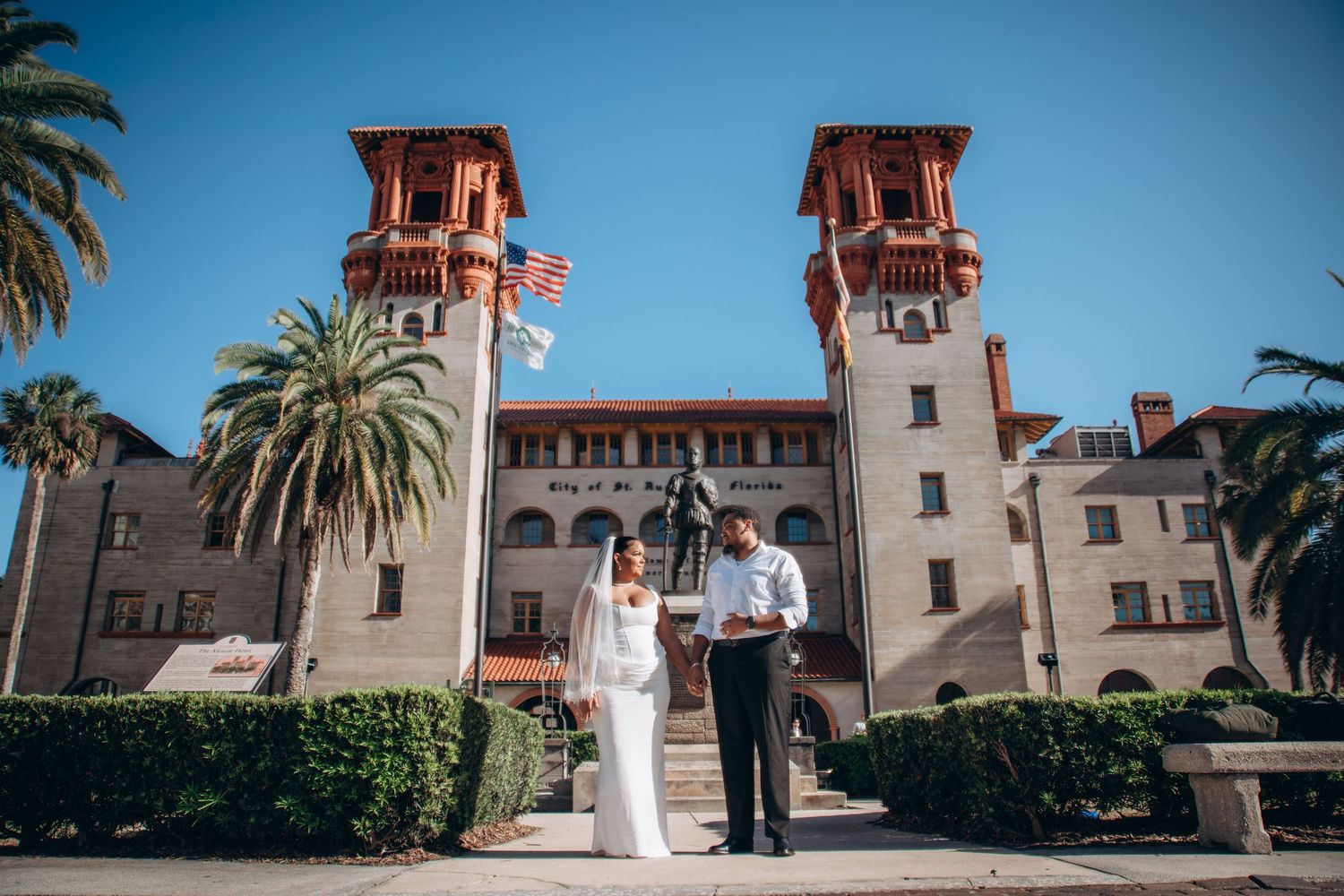 Bride and groom pose in front of historic Lightner Museum with Spanish Renaissance towers in St. Augustine, Florida.