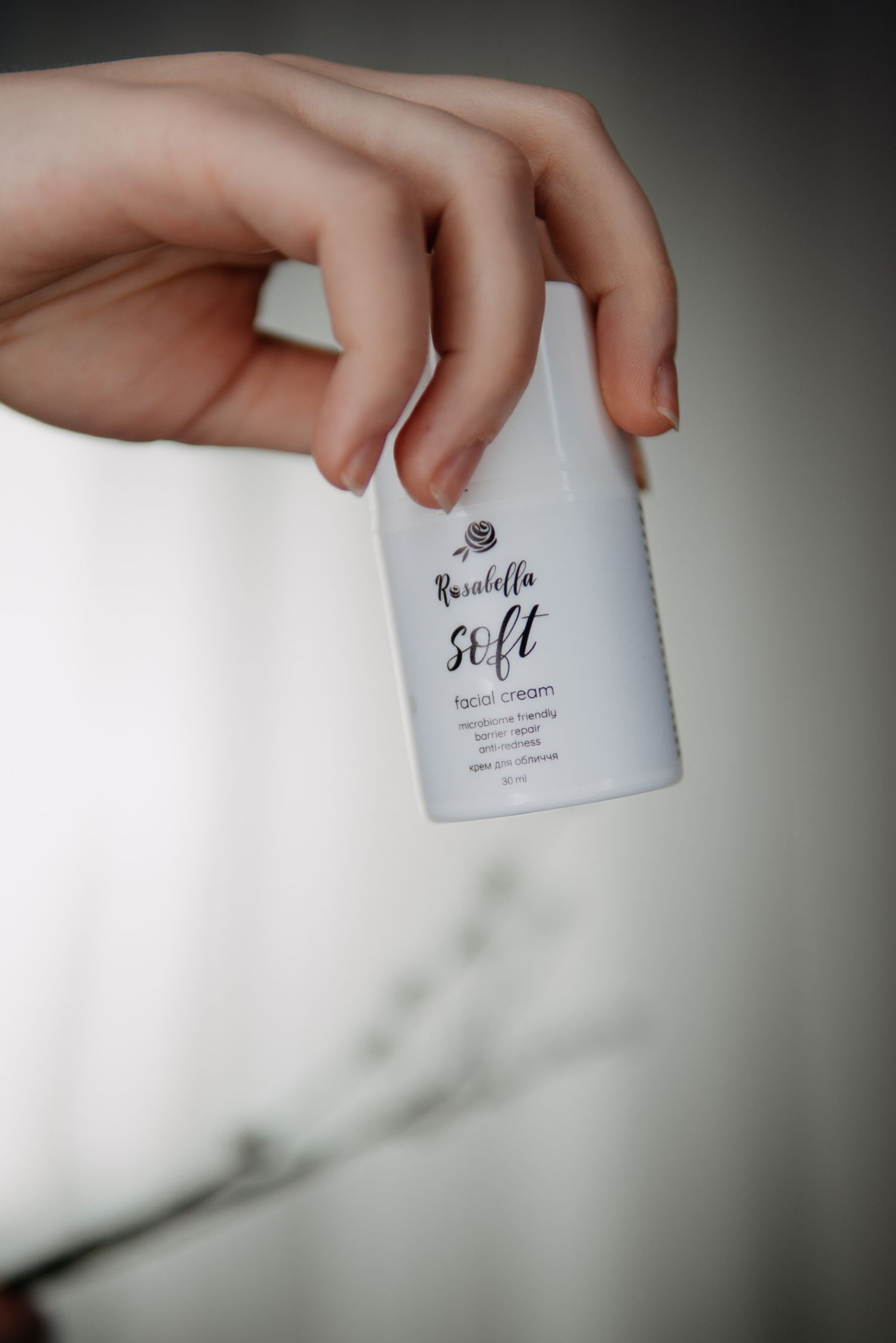 Hand holding Rurabella Soft facial cream bottle, a small white skincare product with elegant minimalist label design.