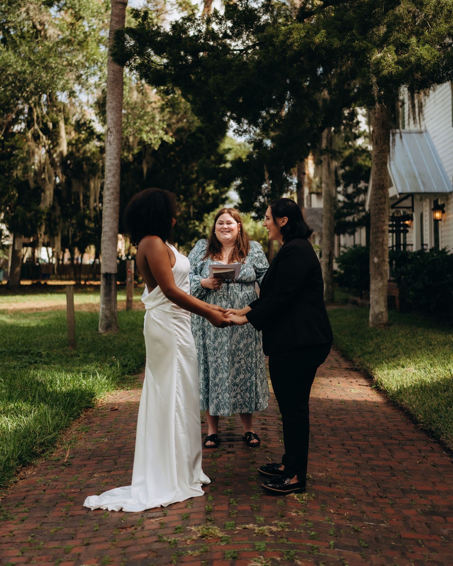 Wedding ceremony taking place on a scenic brick pathway with trees.