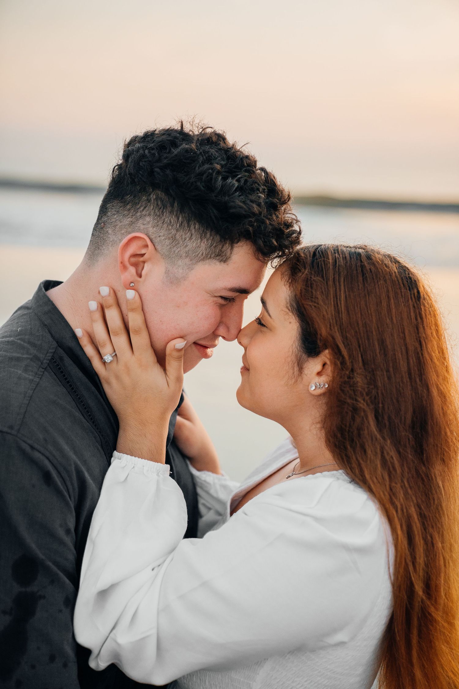 A romantic couple sharing an intimate moment at sunset on the beach.