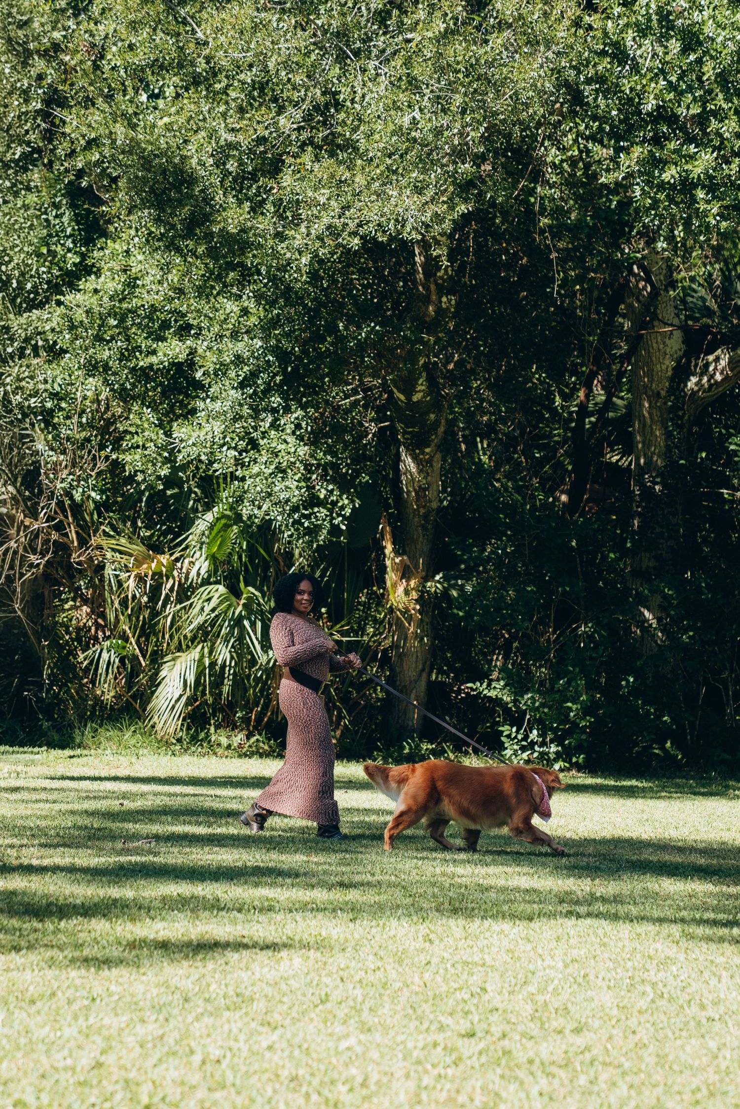 A couple and their dog enjoy time together in a lush green park setting.