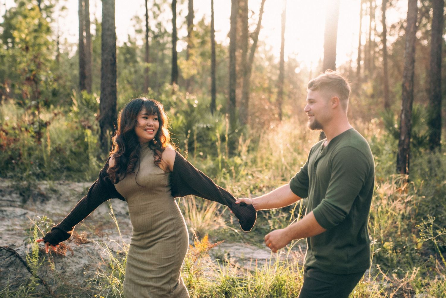 A romantic forest engagement photoshoot with golden sunlight filtering through tall trees.
