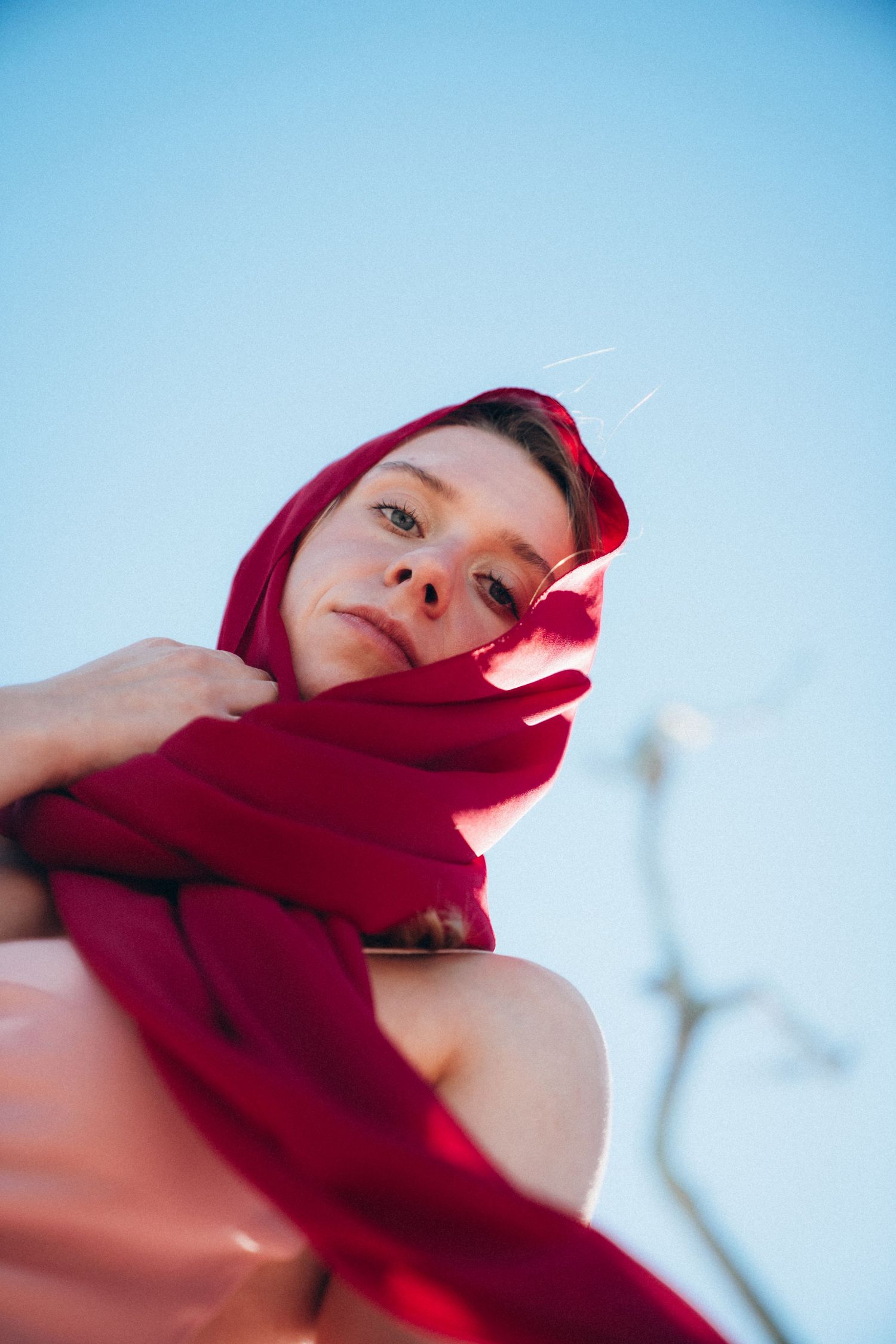 A series of artistic shots featuring a red scarf against a bright blue sky background.