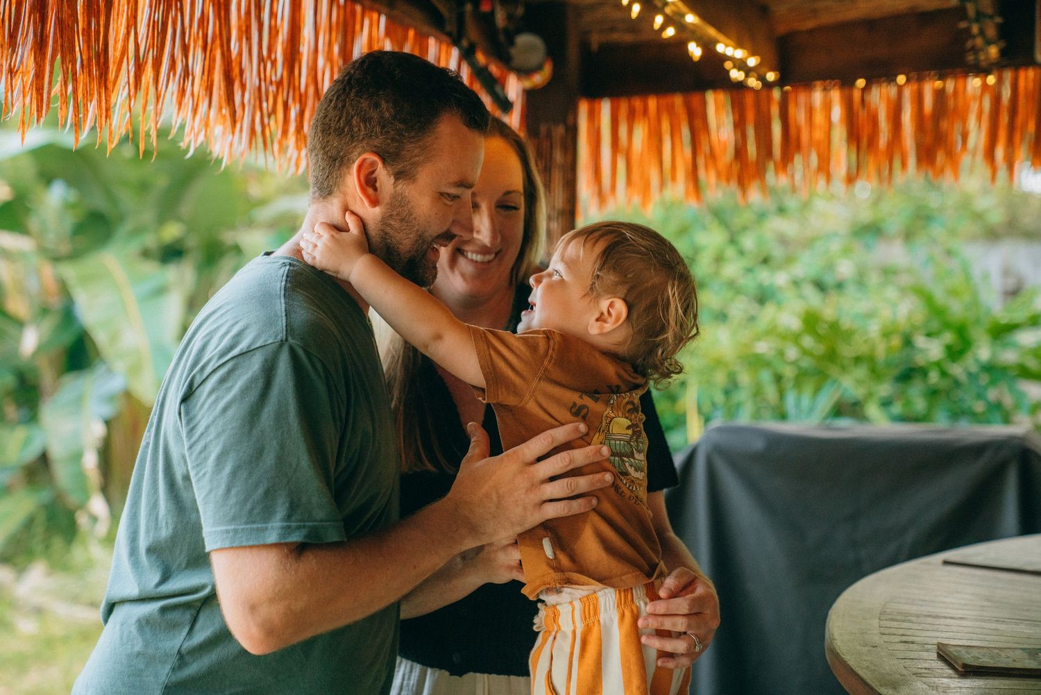 A joyful scene under a thatched roof with orange hammock creating a cozy atmosphere.