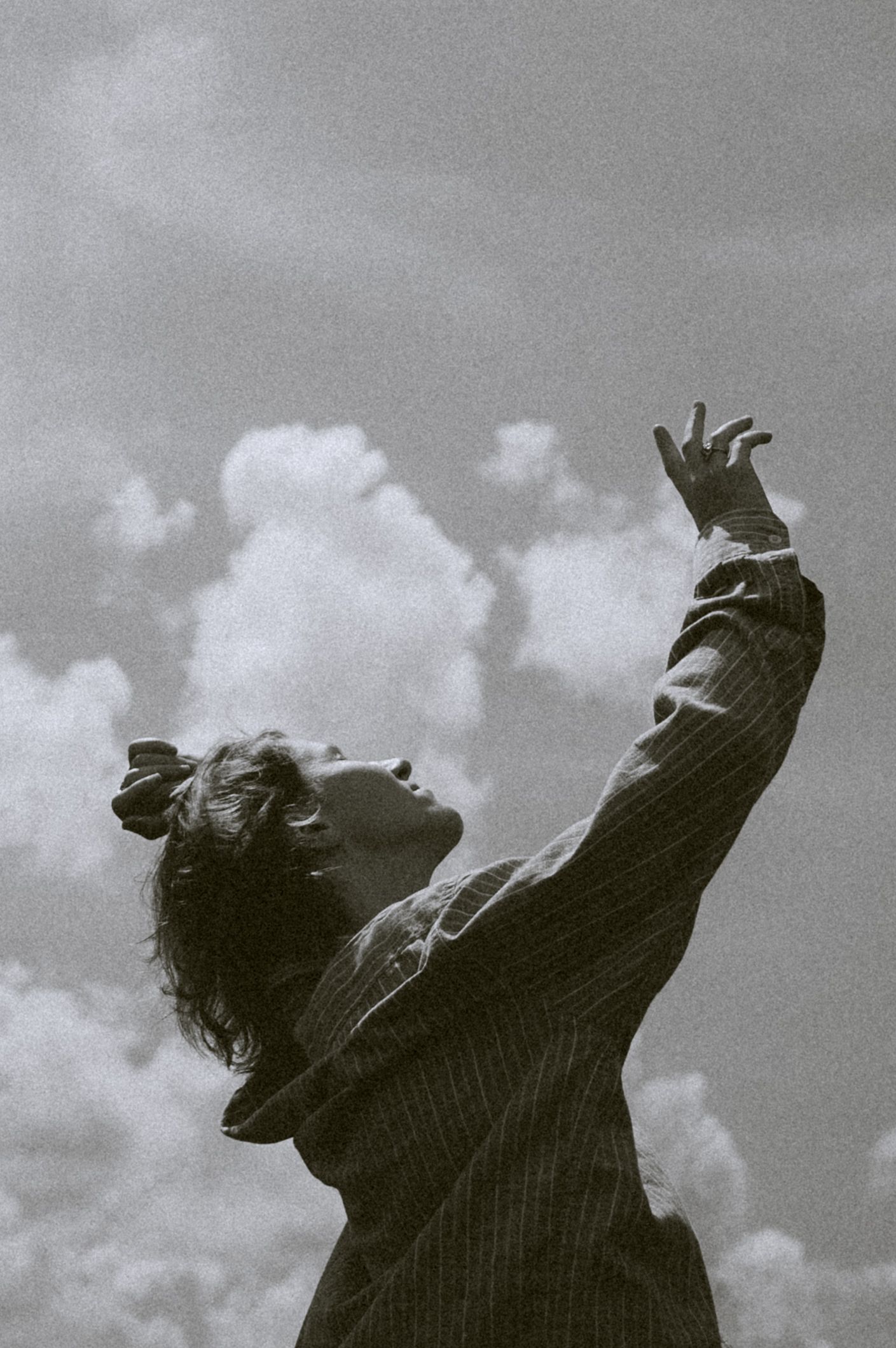 Black and white photo series of person reaching upward against cloudy sky.