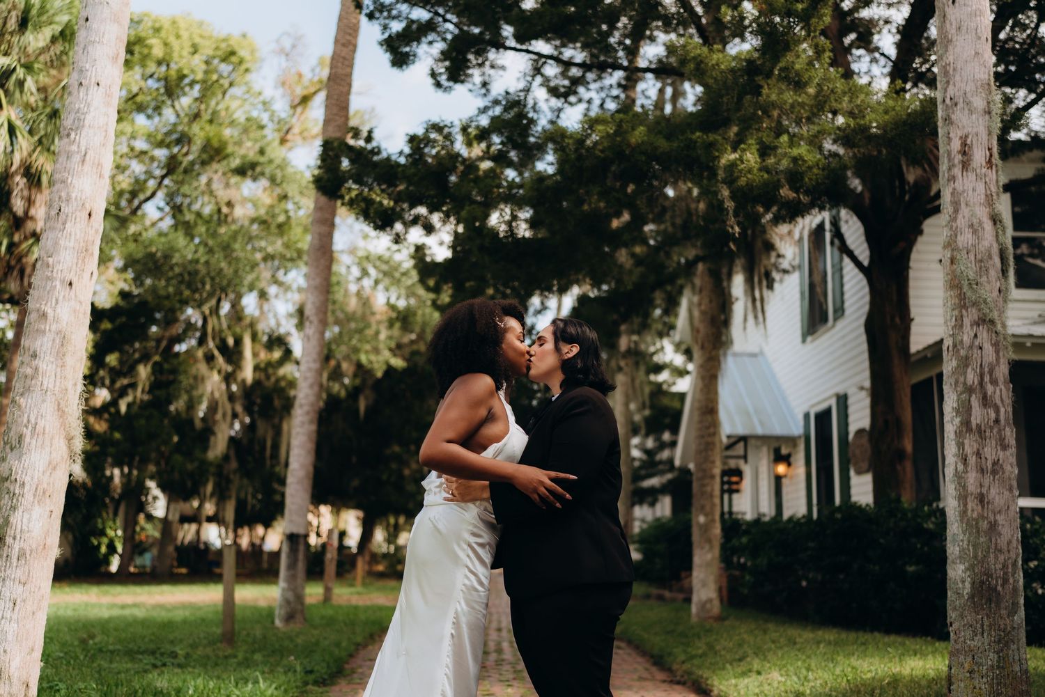 A romantic moment between newlyweds on a palm tree-lined path.