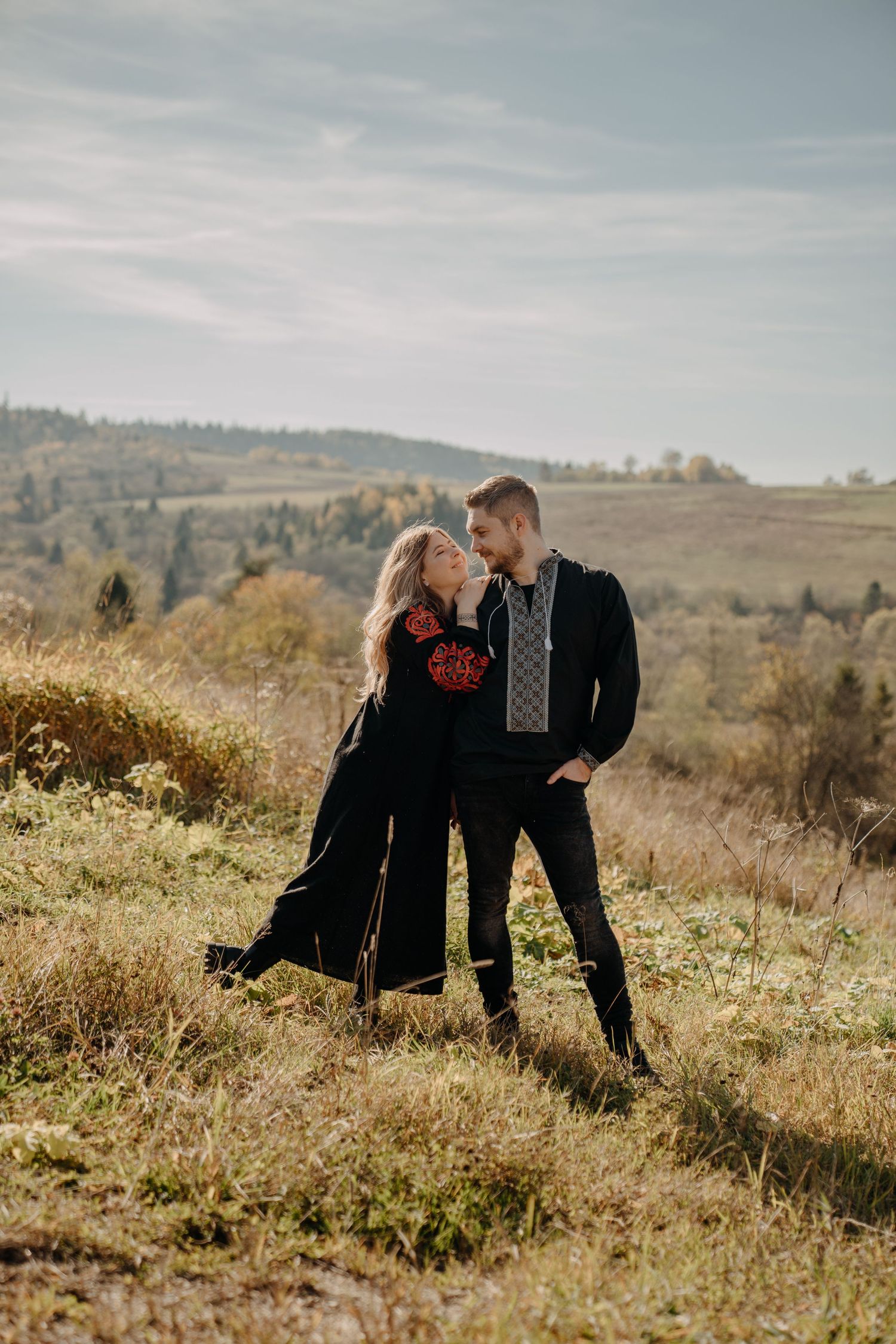 Couple shares romantic moments on a hillside during an autumn photoshoot.