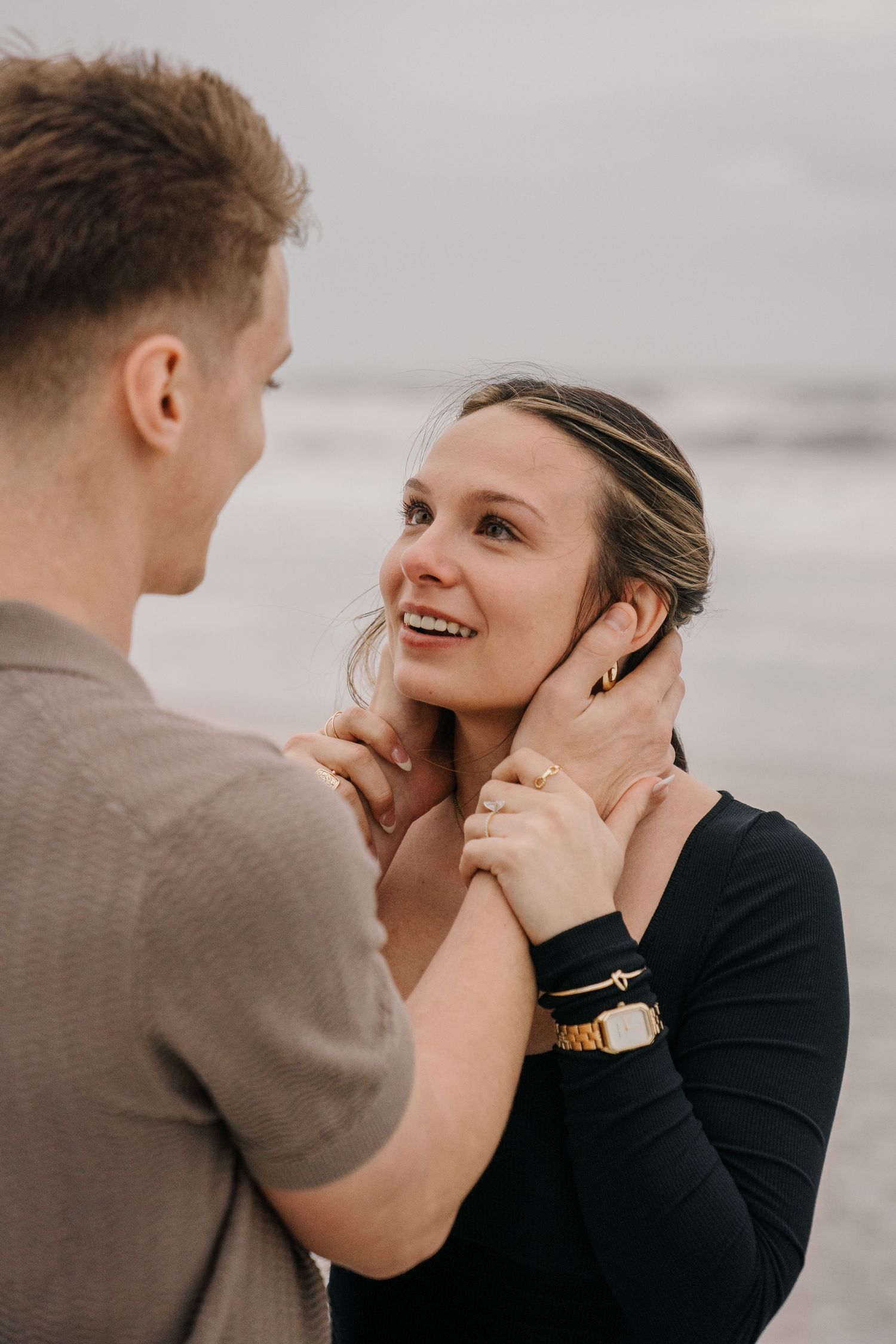 Close-up shots of a couple laughing and embracing on an overcast beach day.