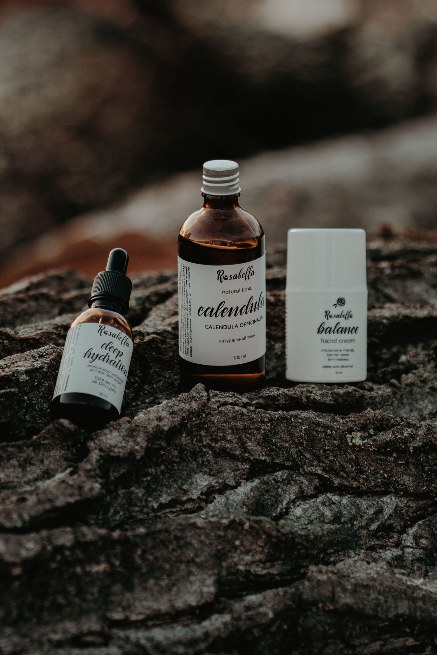 Rosabella calendula oil, face serum, and balance cream displayed on natural rock.