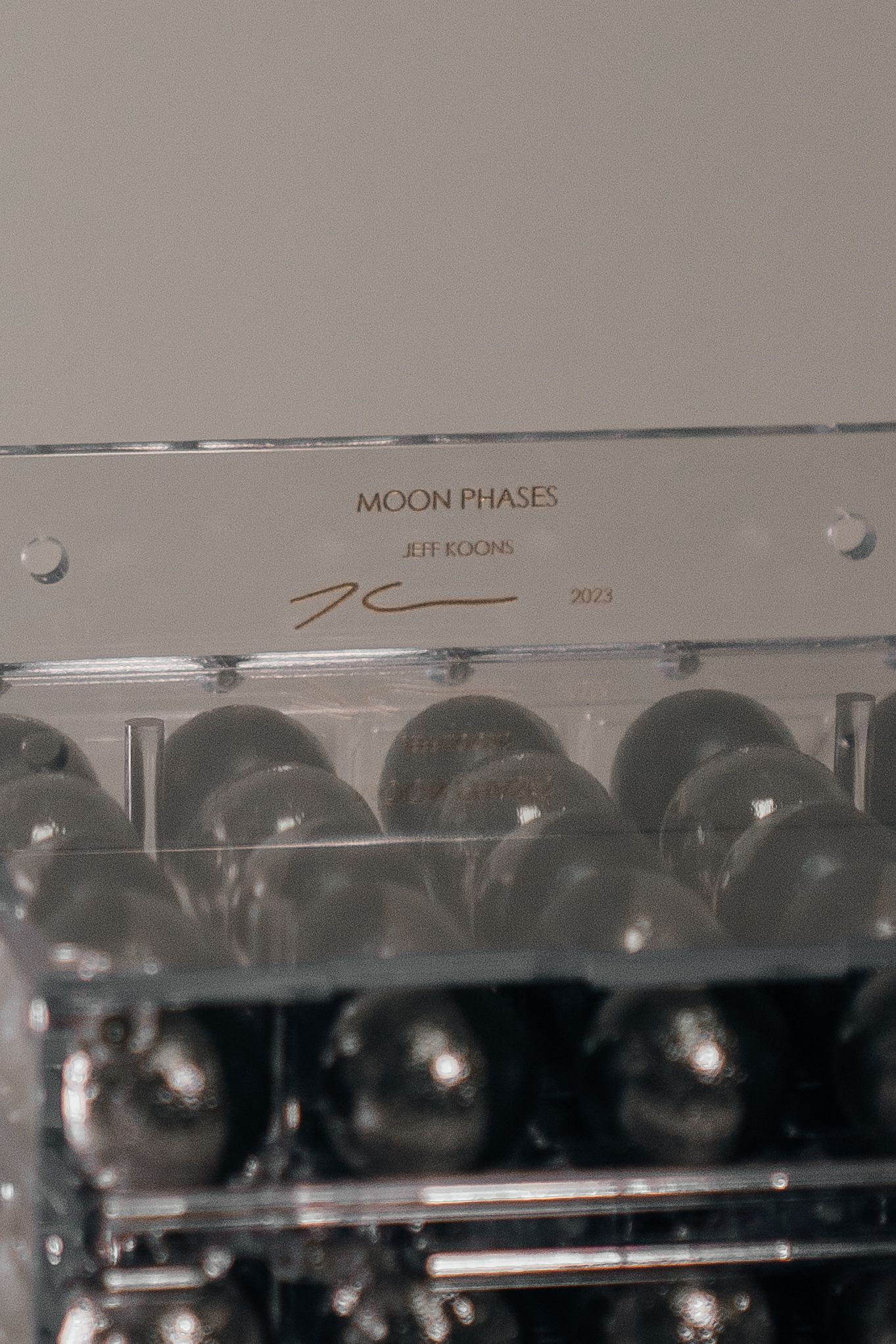 Jeff Koons Moon Phases 2023 signed artwork in clear acrylic case with dark metallic spheres.
