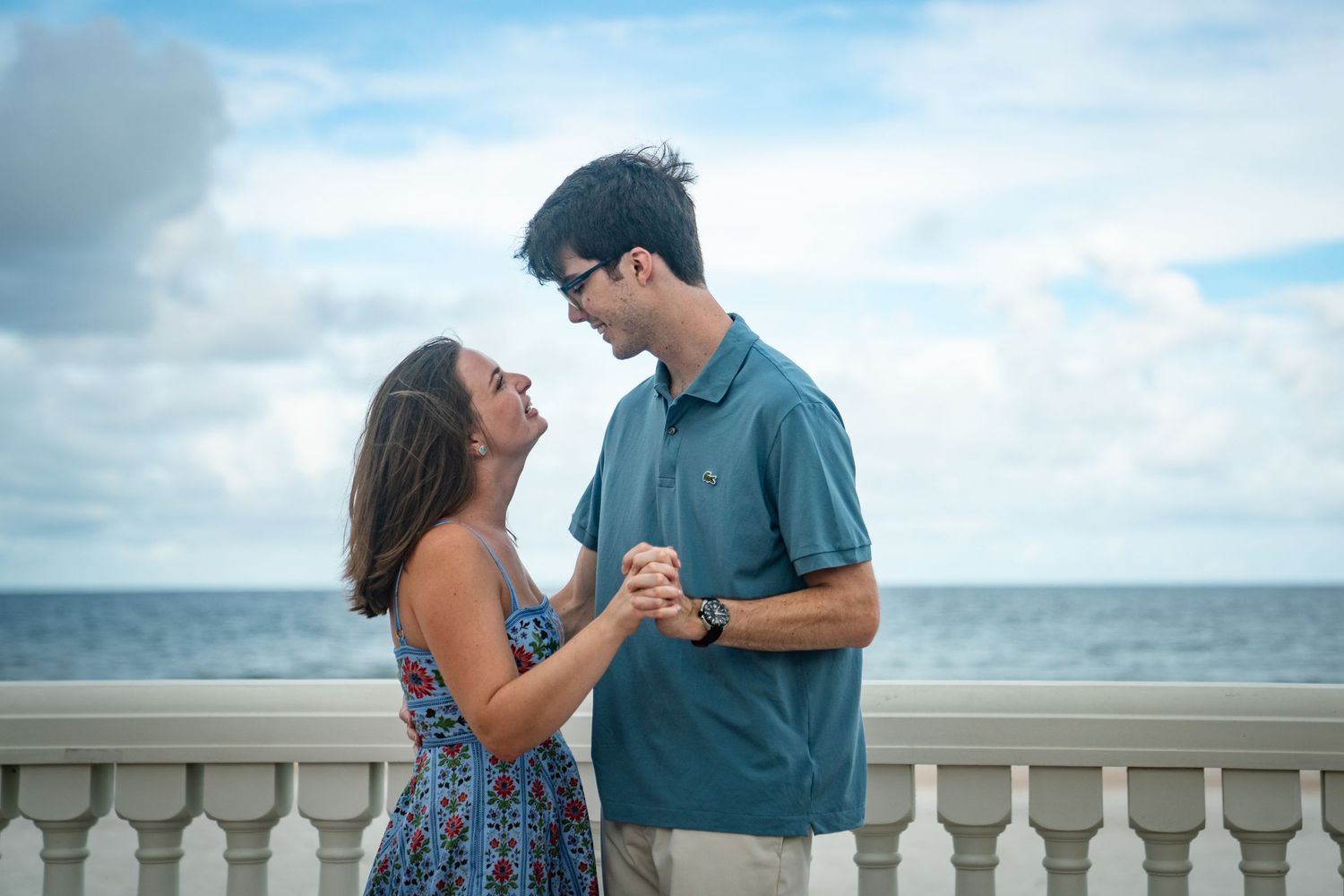 Romantic couple shares tender moments together on a beach boardwalk during a cloudy afternoon.