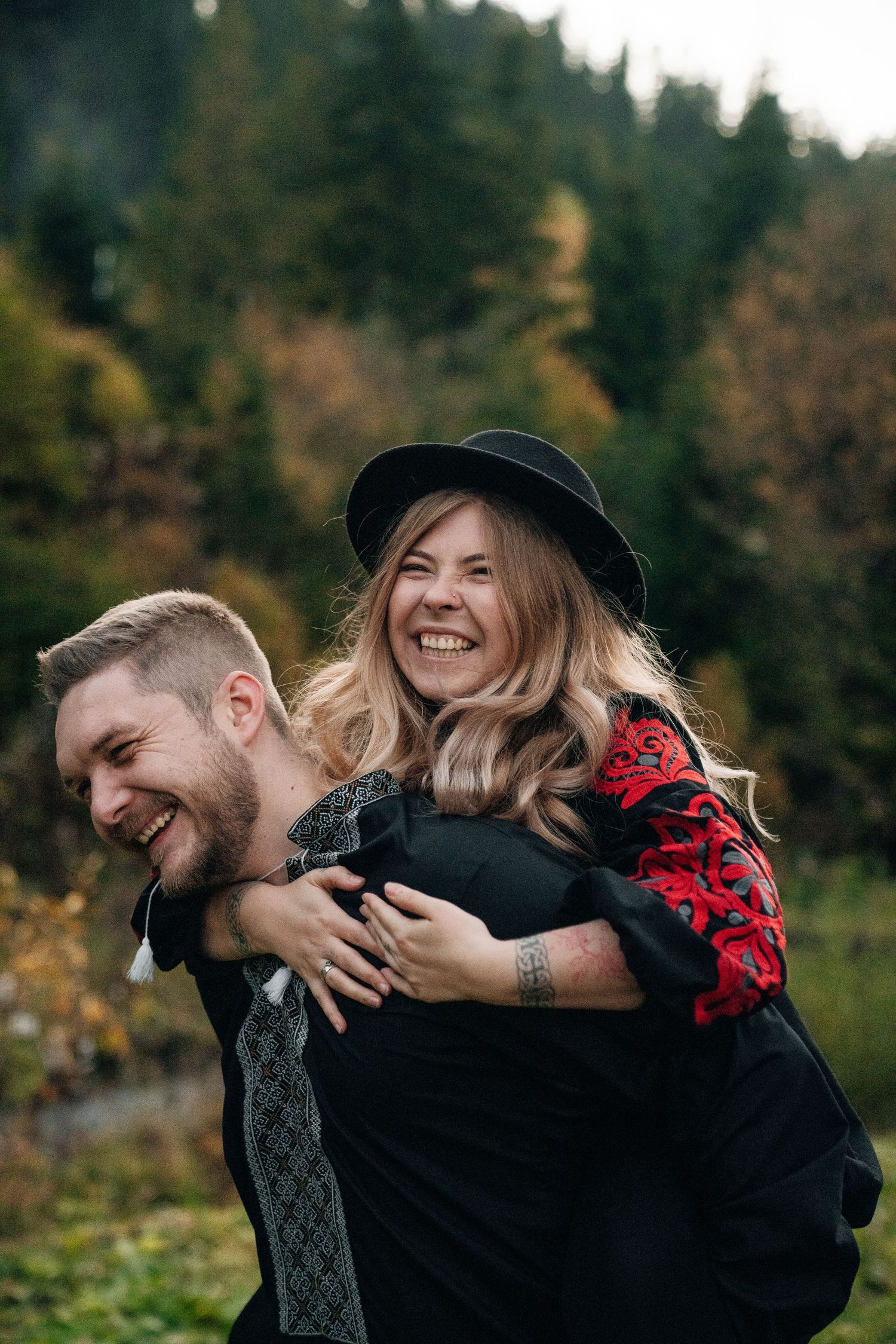 Playful piggyback ride moment captured in autumn mountain setting with evergreen forest backdrop.