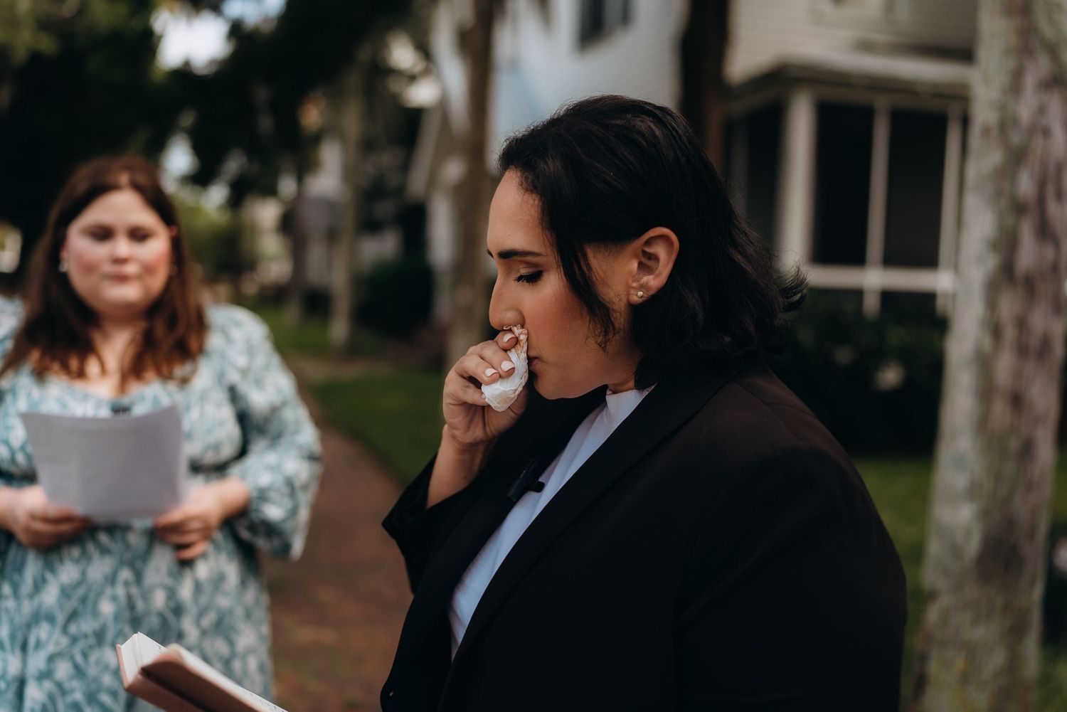 A person wipes away tears during an emotional outdoor wedding ceremony.