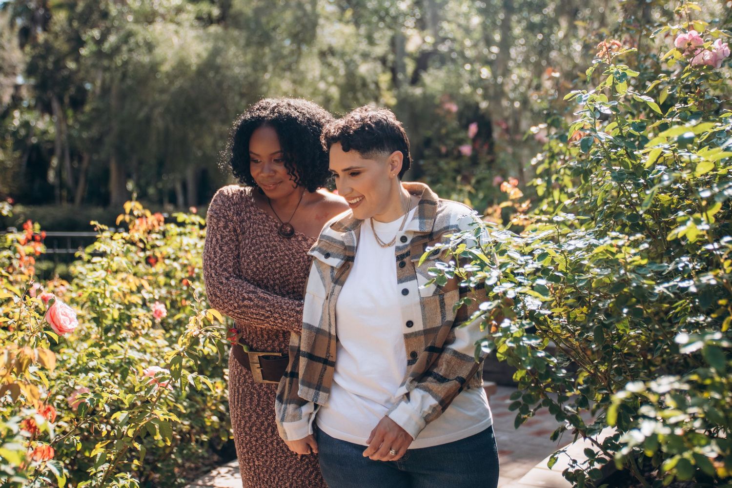 Couple sharing tender moments together in a lush garden setting with blooming flowers and greenery.