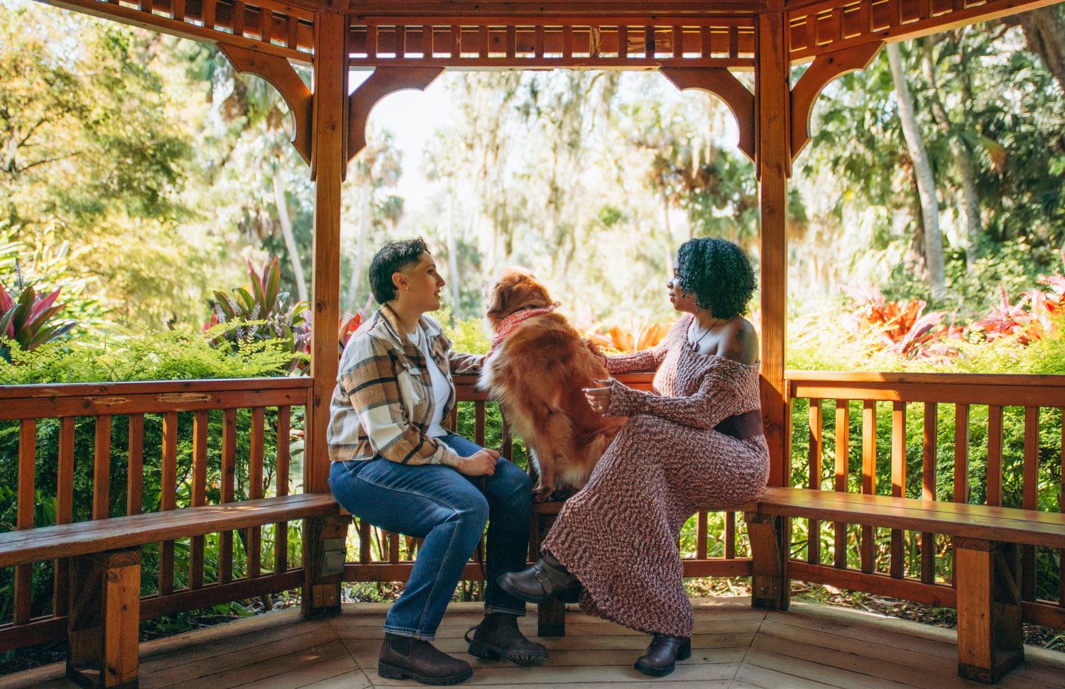 A couple shares a moment together in a wooden gazebo surrounded by lush tropical gardens.