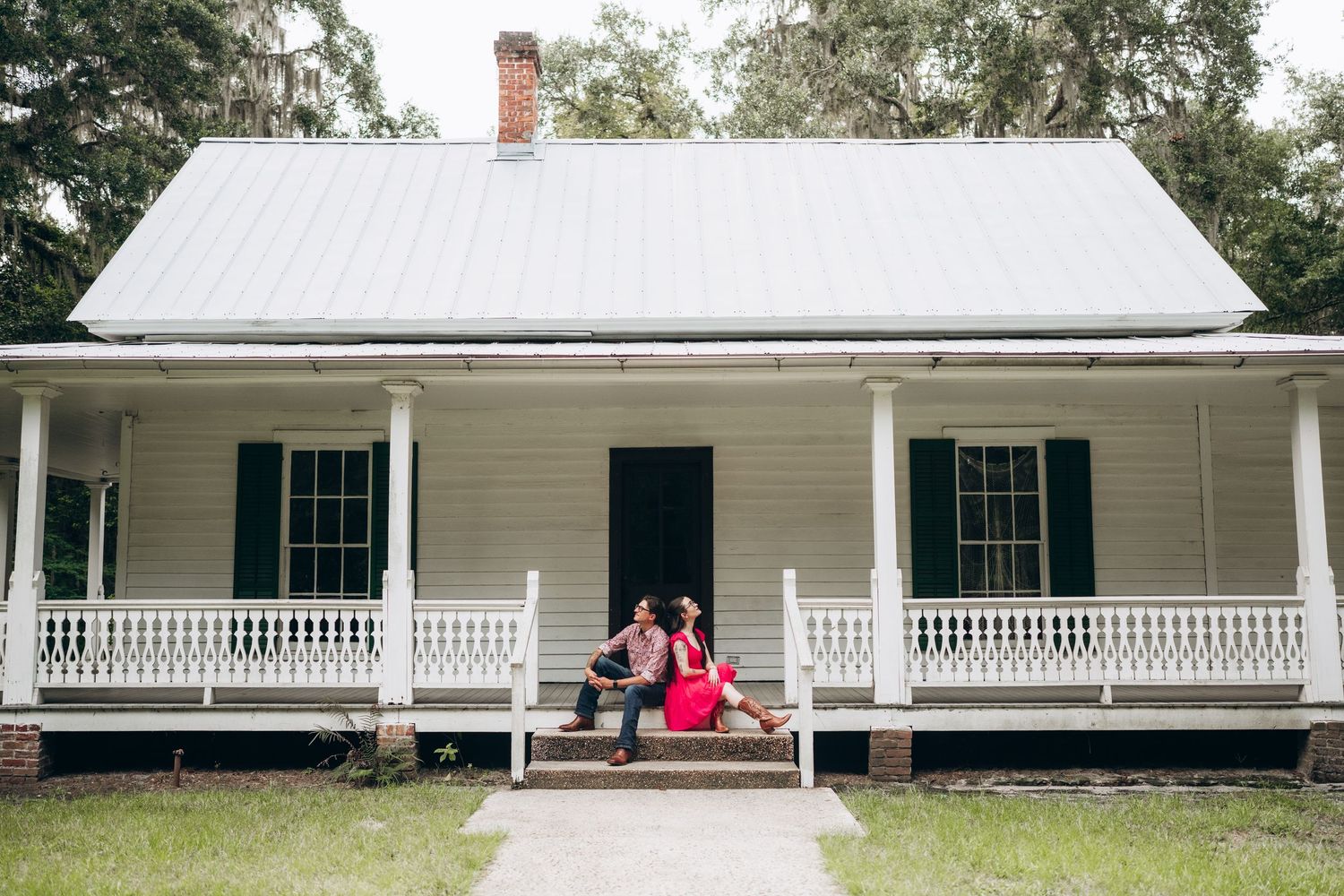 Long white plantation-style house with covered porch and green shutters stretches across the landscape.
