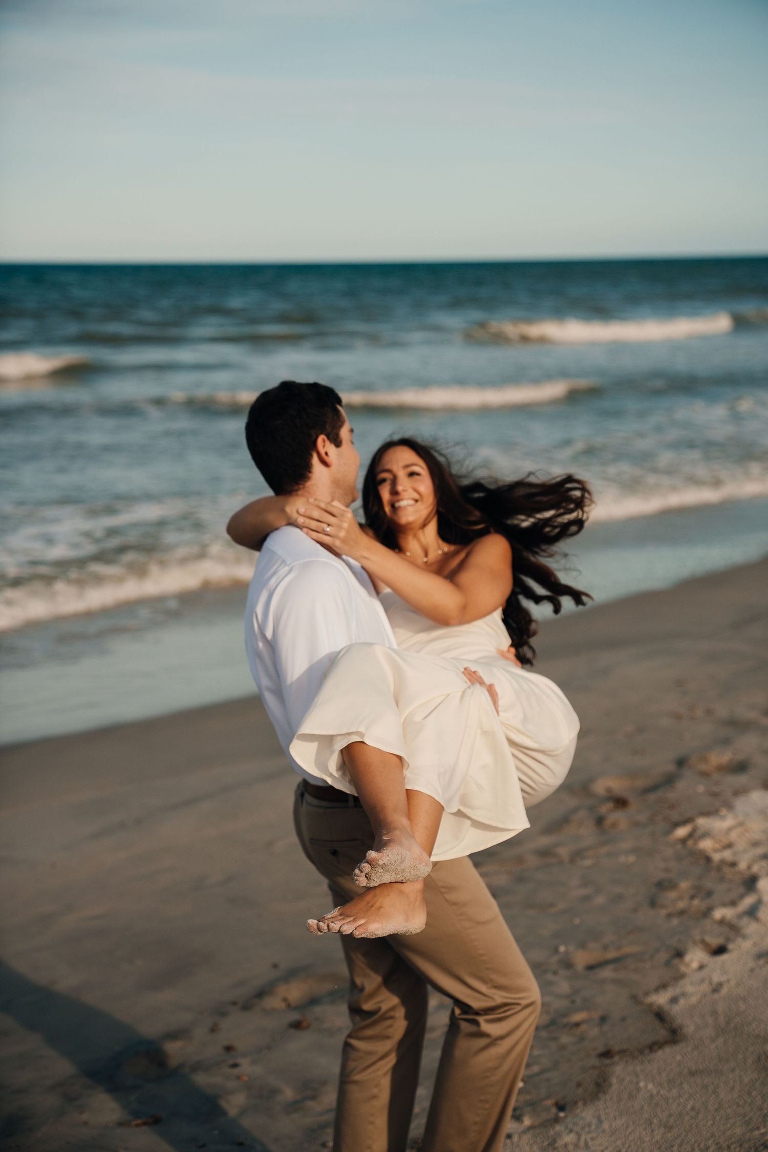 A romantic moment captured between a couple dancing on the beach at sunset.
