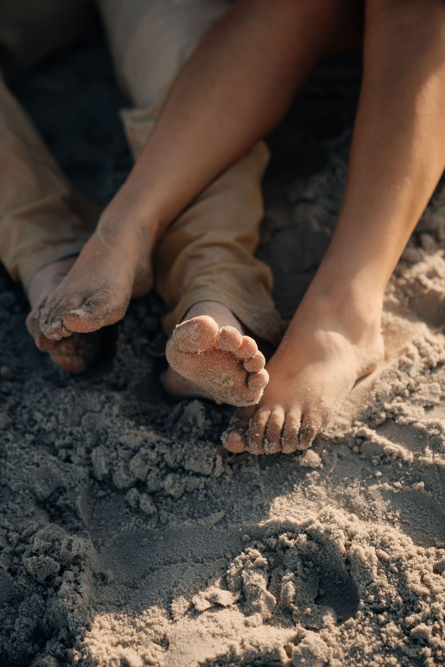Sandy feet on the beach with gentle waves in the background.