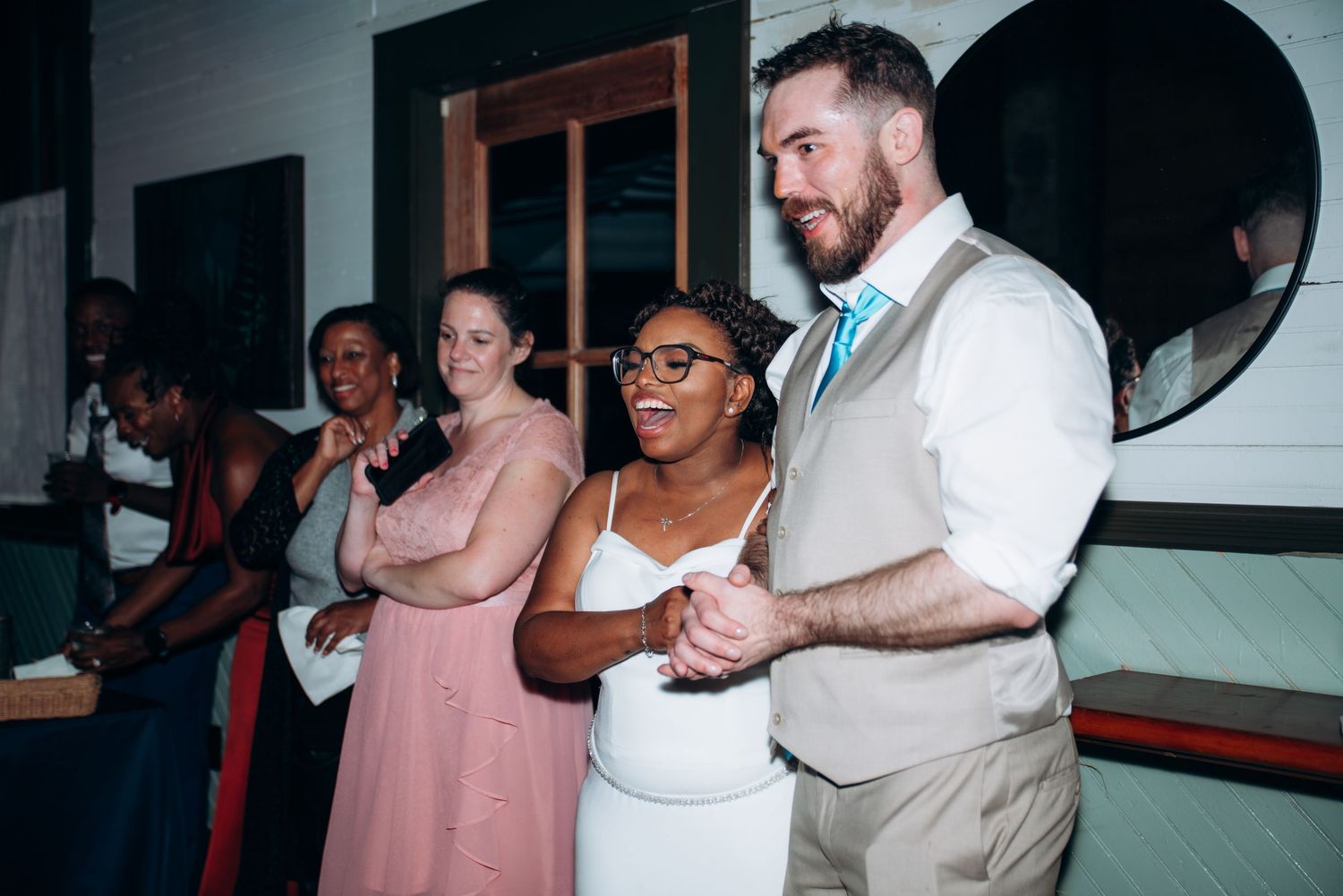 Bride and groom share a dance at wedding reception with guests watching in background.