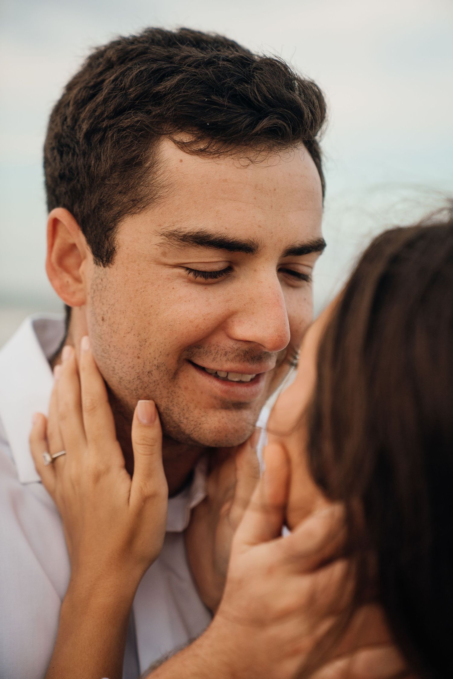 An intimate close-up sequence of a tender moment between two people on a beach.