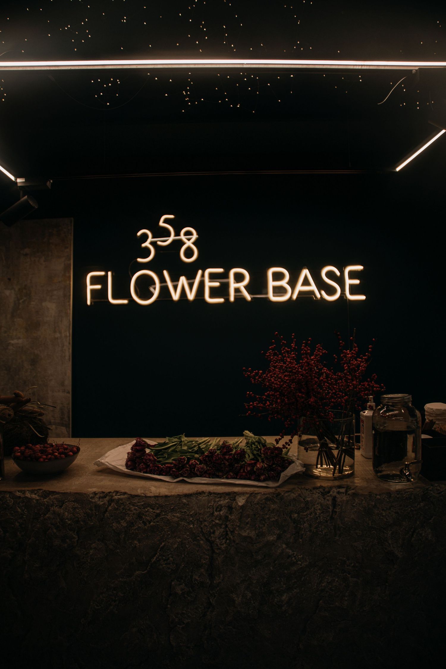 358 Flower Base shop glowing neon sign above a floral display counter.