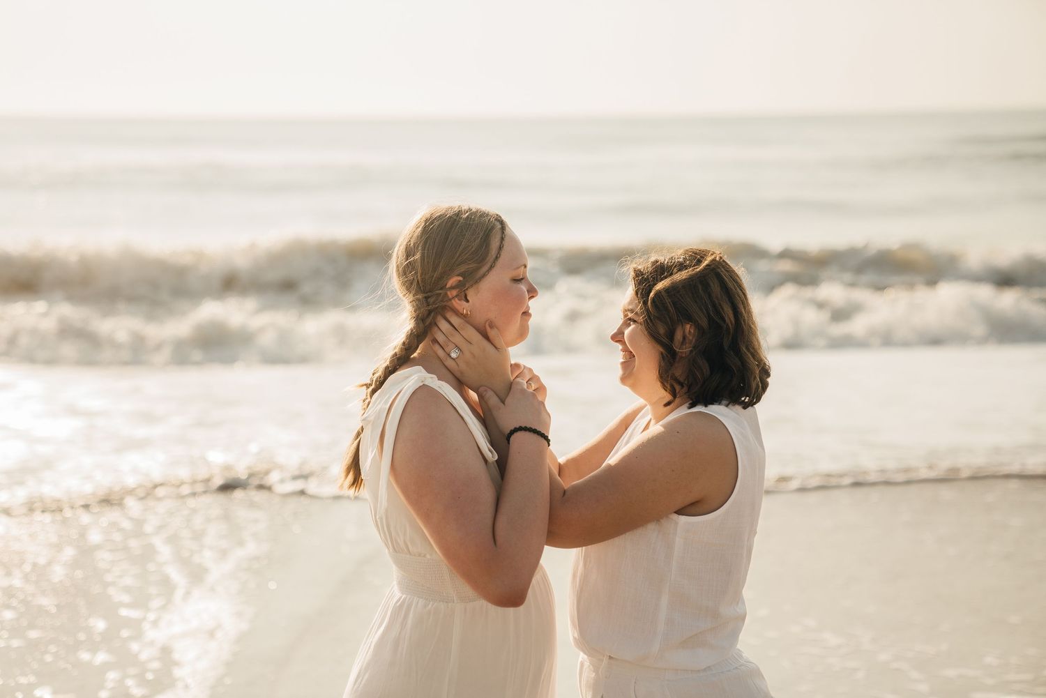 Two people embracing on a sandy beach during golden hour.