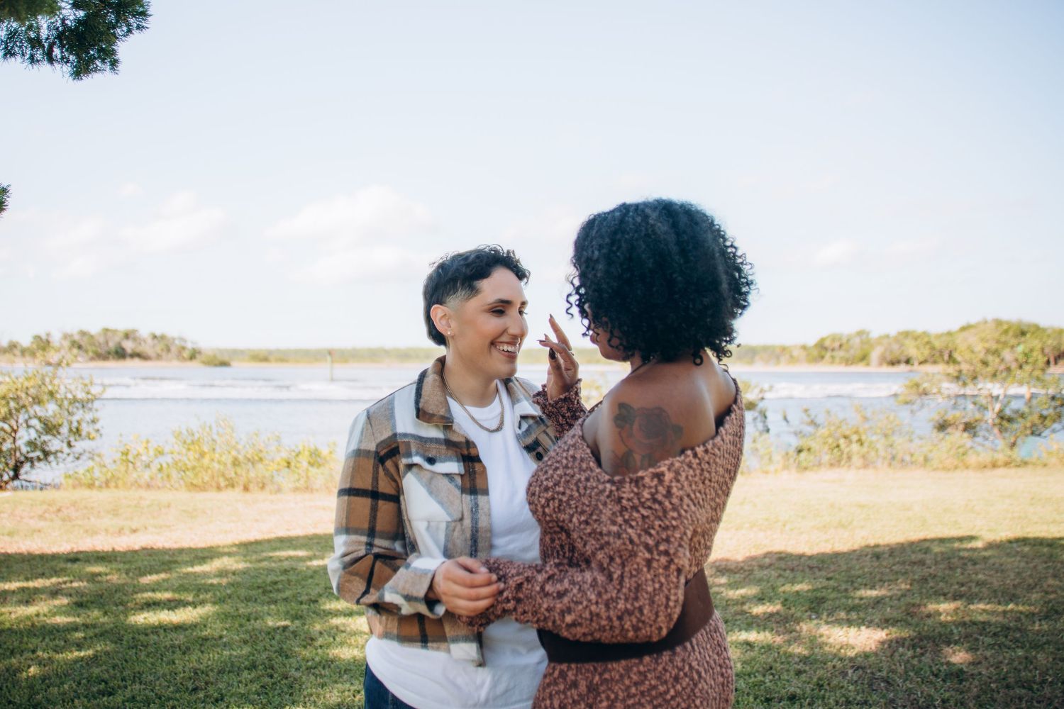 A couple embraces while walking along a scenic waterfront path on a sunny autumn day.