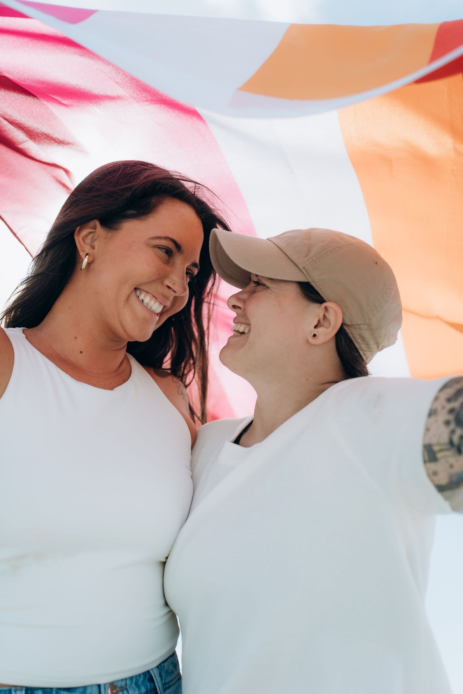 A joyful couple sharing intimate moments on the beach while wearing white tops.
