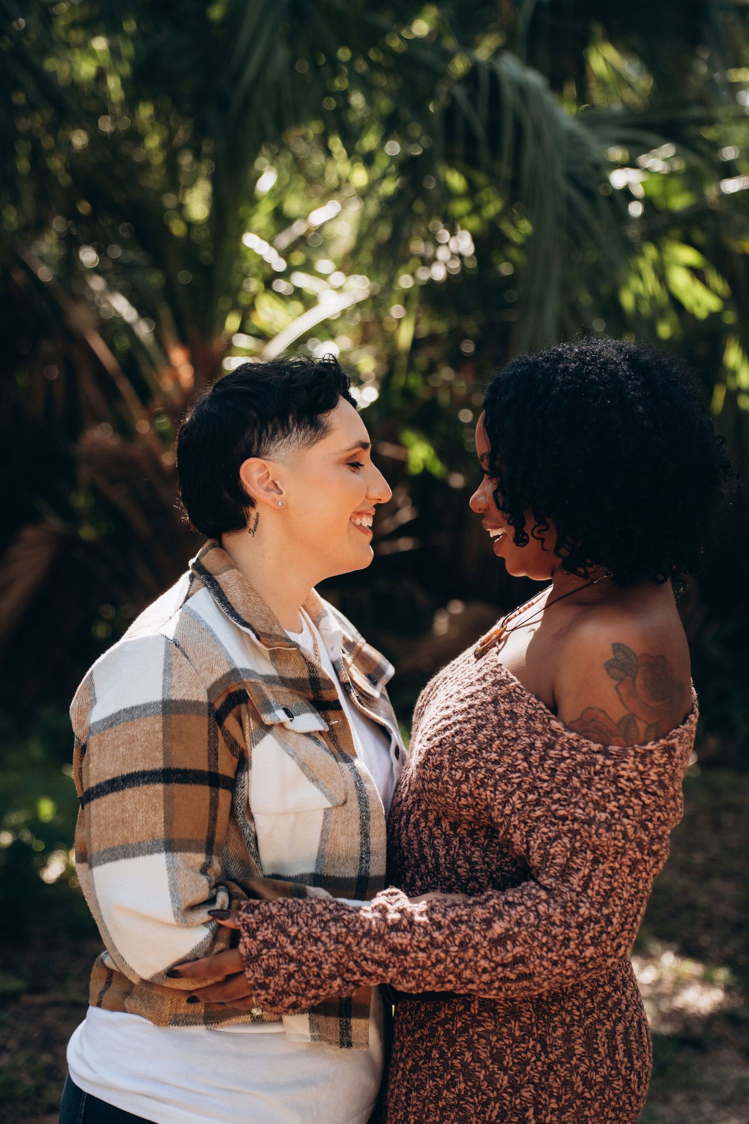 A couple sharing intimate moments while posing together in a sun-dappled forest setting.