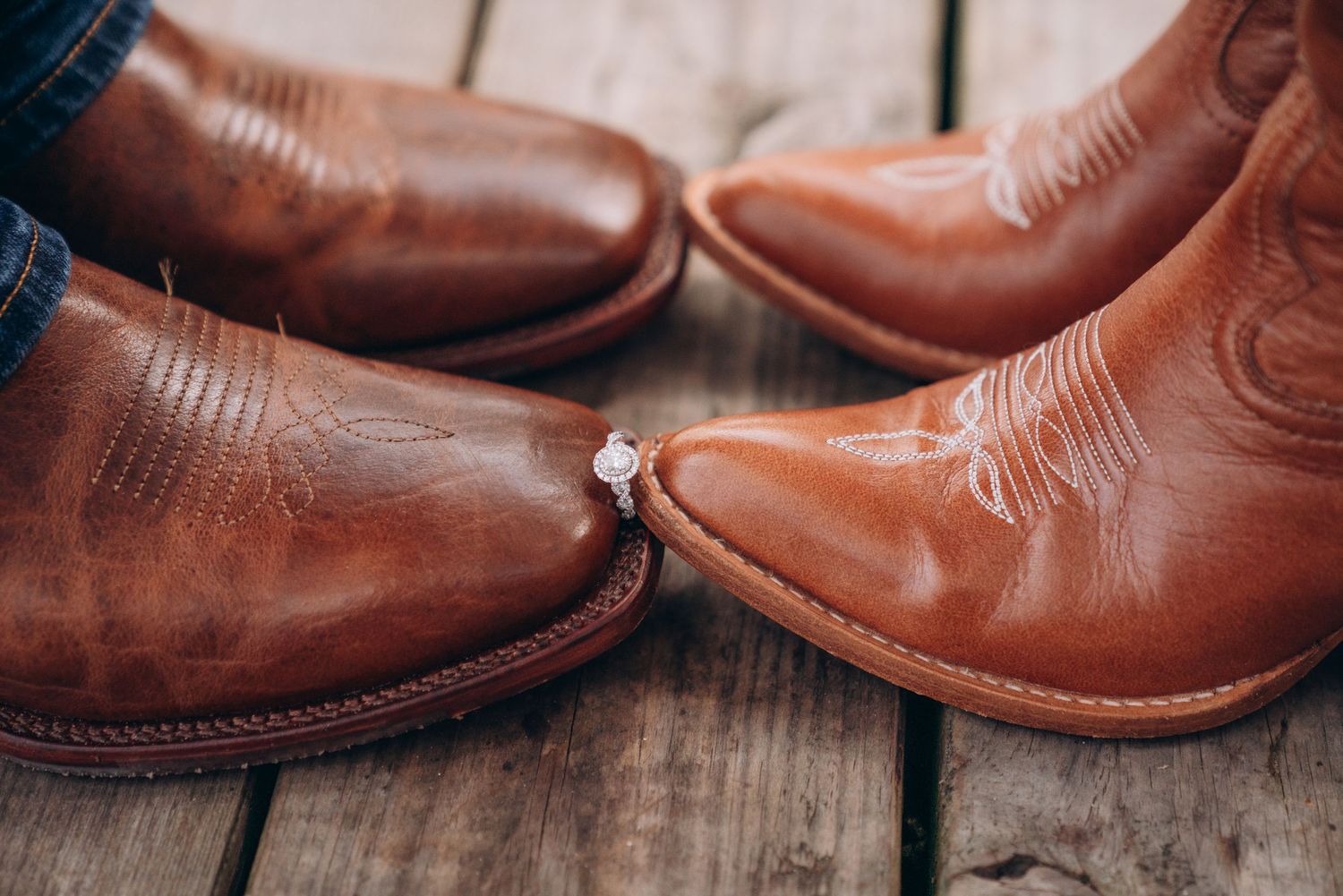 Brown leather cowboy boots arranged in pairs on a rustic wooden surface.