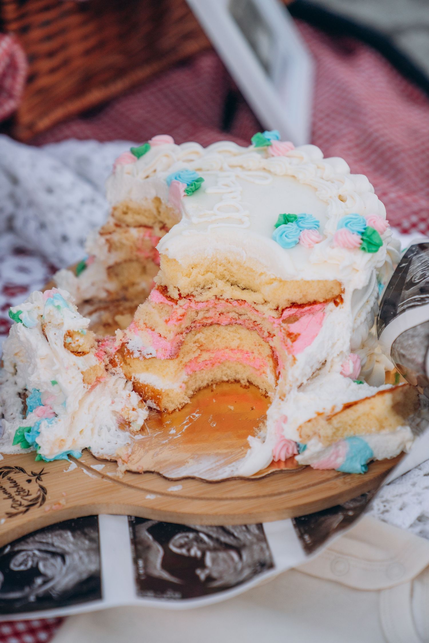 A series of close-up shots showing a white frosted cake with pink filling being cut and served on a wooden board.