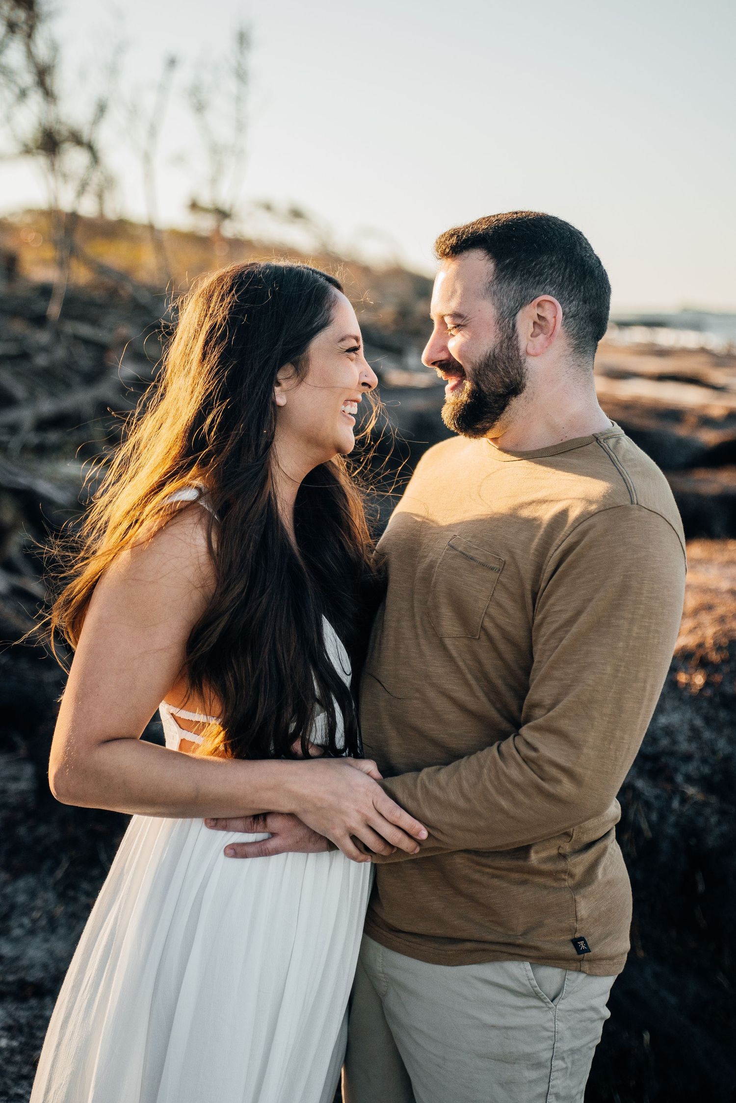 A joyful moment shared between two people on rocky coastal terrain at sunset.