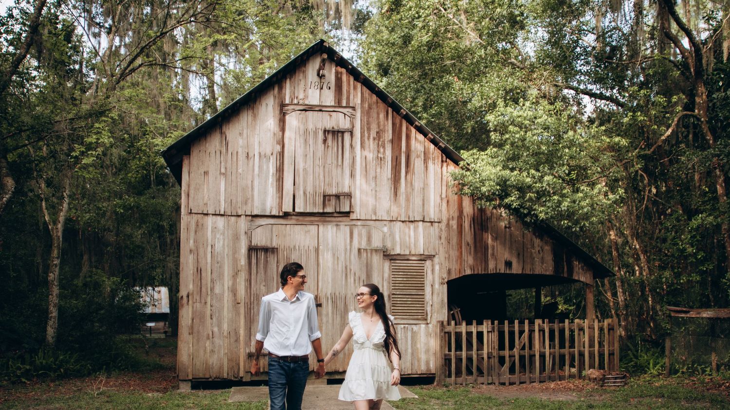 A rustic wooden barn provides a scenic backdrop for a romantic countryside photo session.