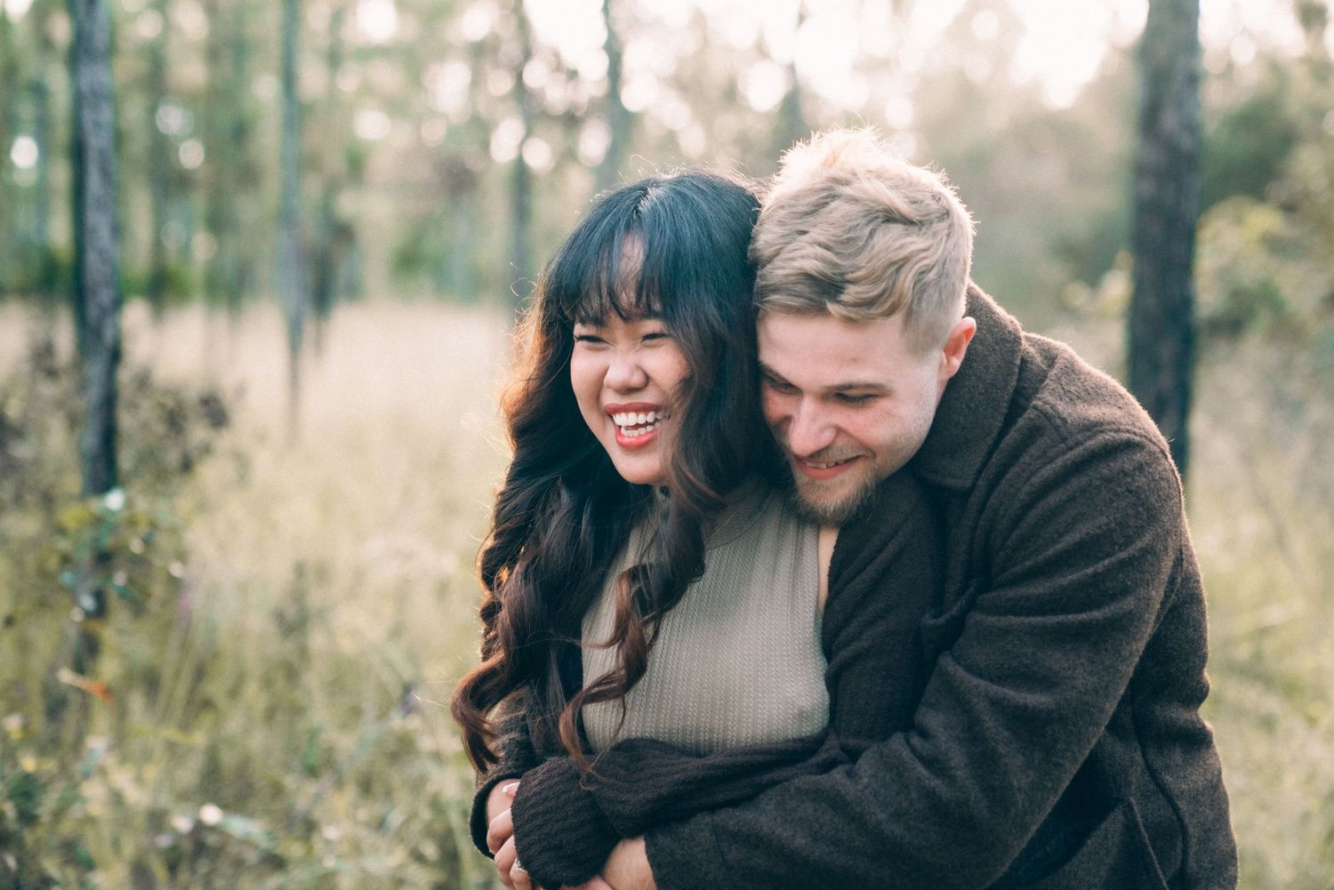 Couple sharing joyful moments together in a scenic outdoor forest setting during golden hour.