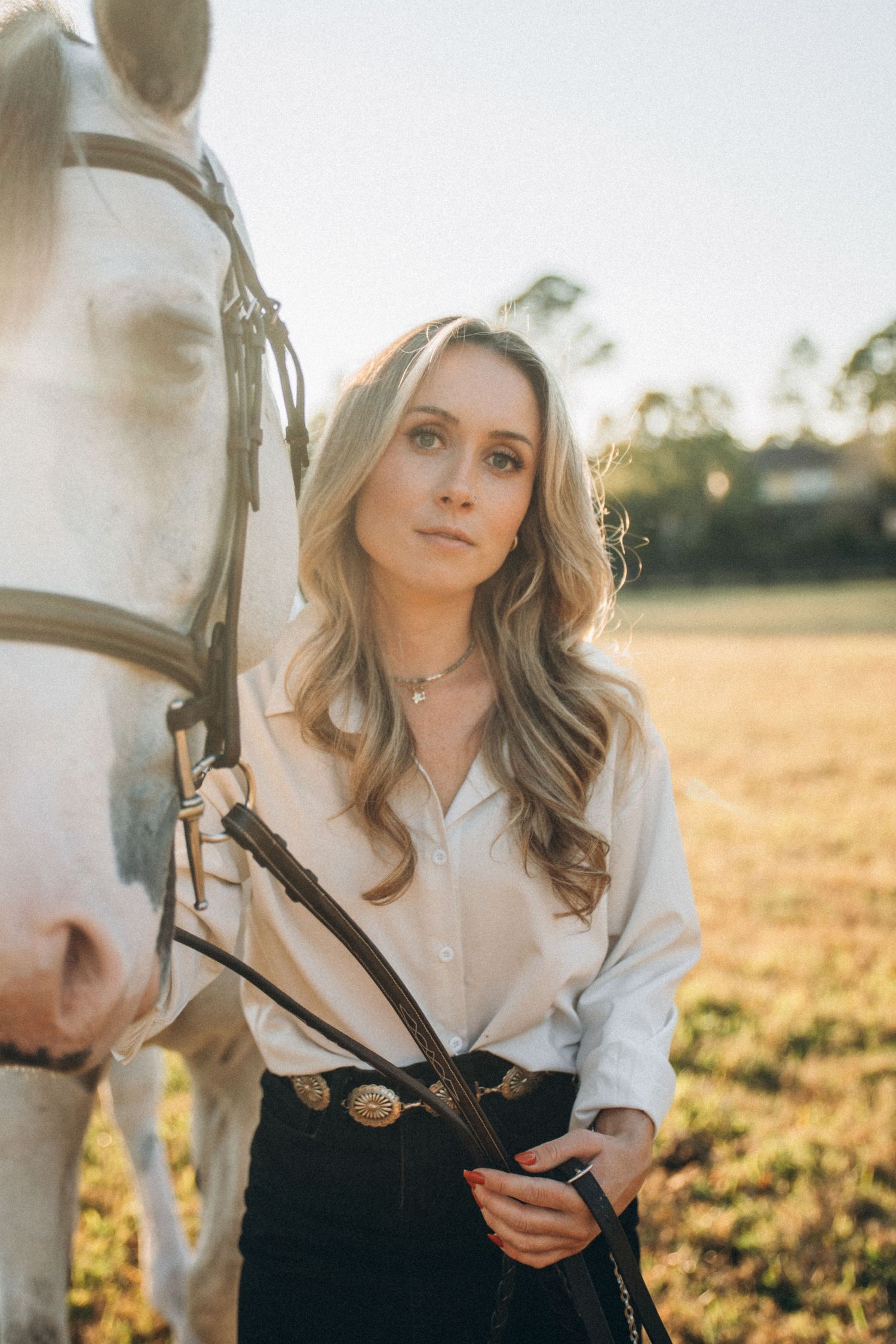 Portrait of a person in white blouse against golden sunset field with dreamy lighting and soft focus.