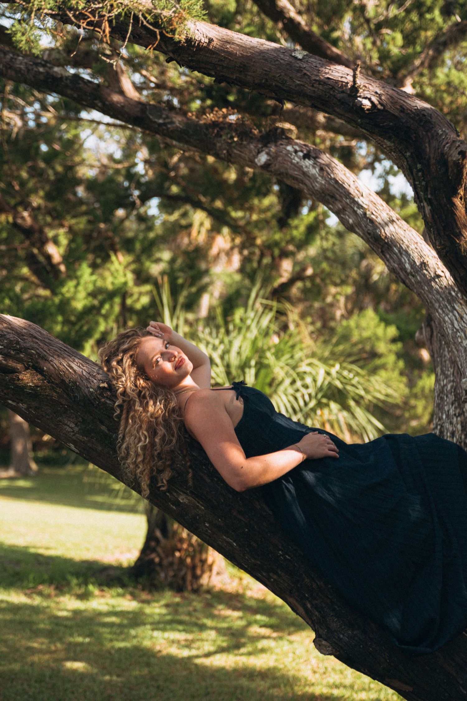 Relaxed moment lying on a tree branch in a navy dress.
