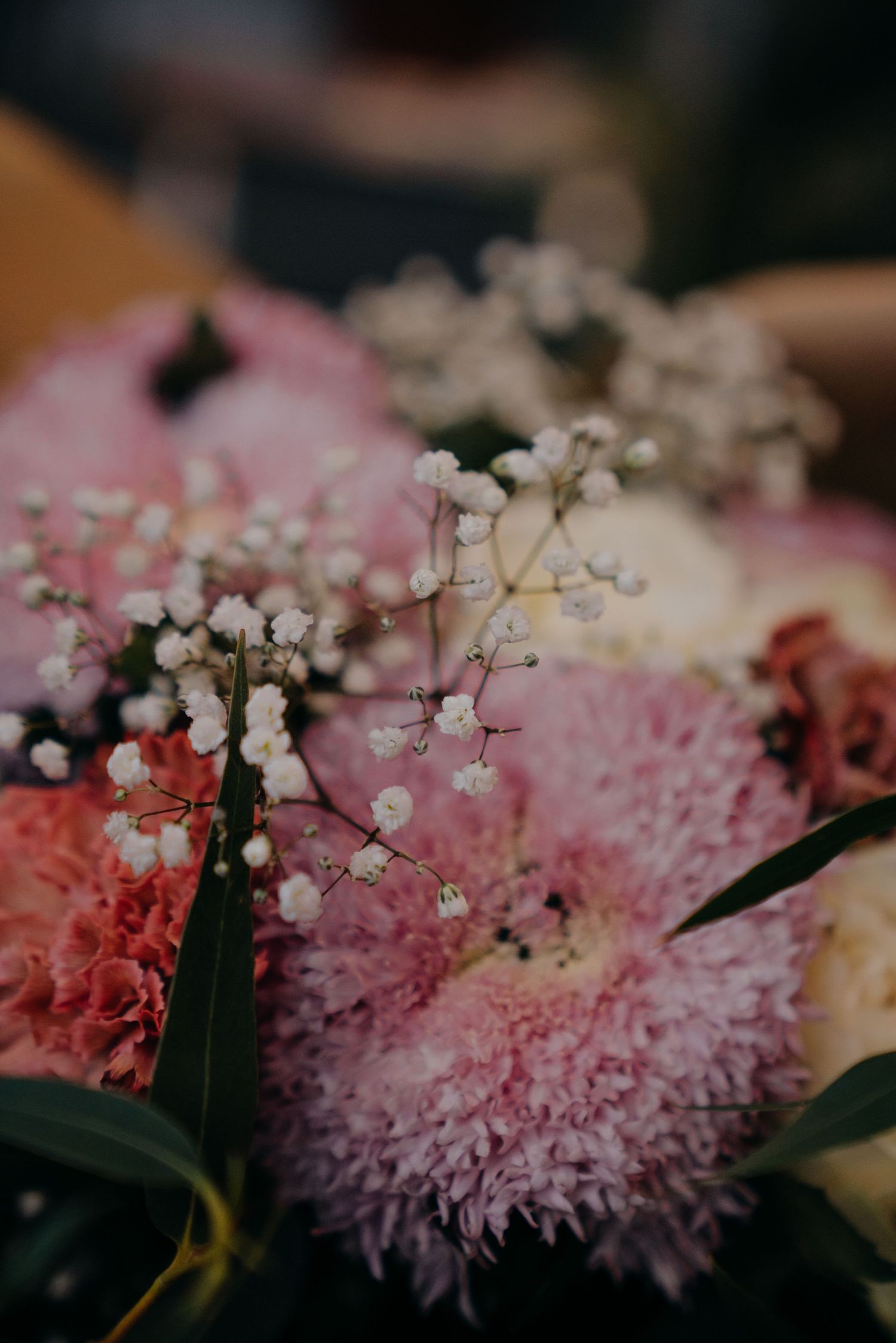 Close-up of a pink floral bouquet featuring chrysanthemums, carnations, and delicate white baby's breath flowers.
