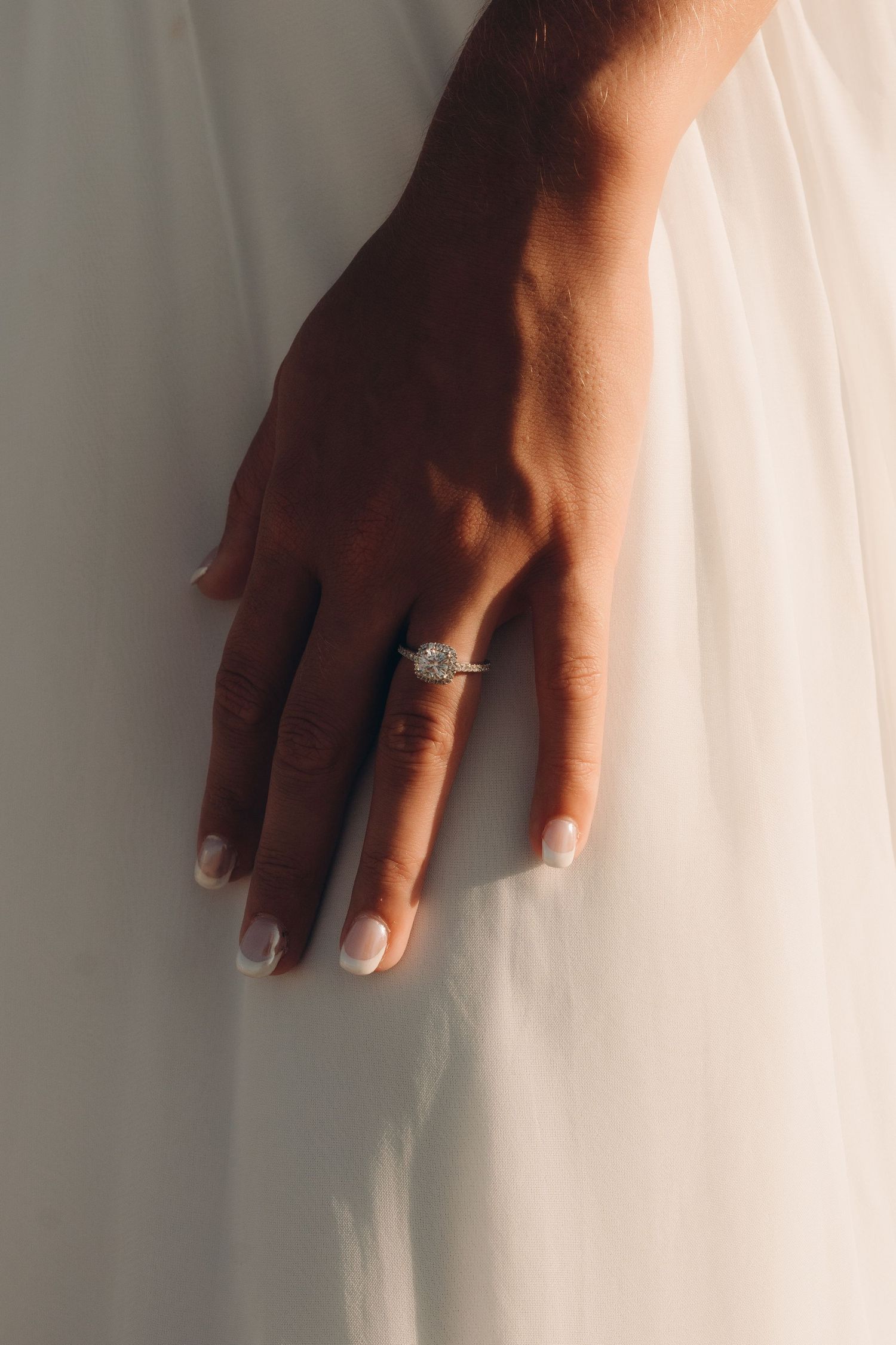 Close-up shot of hands against white fabric with natural lighting.