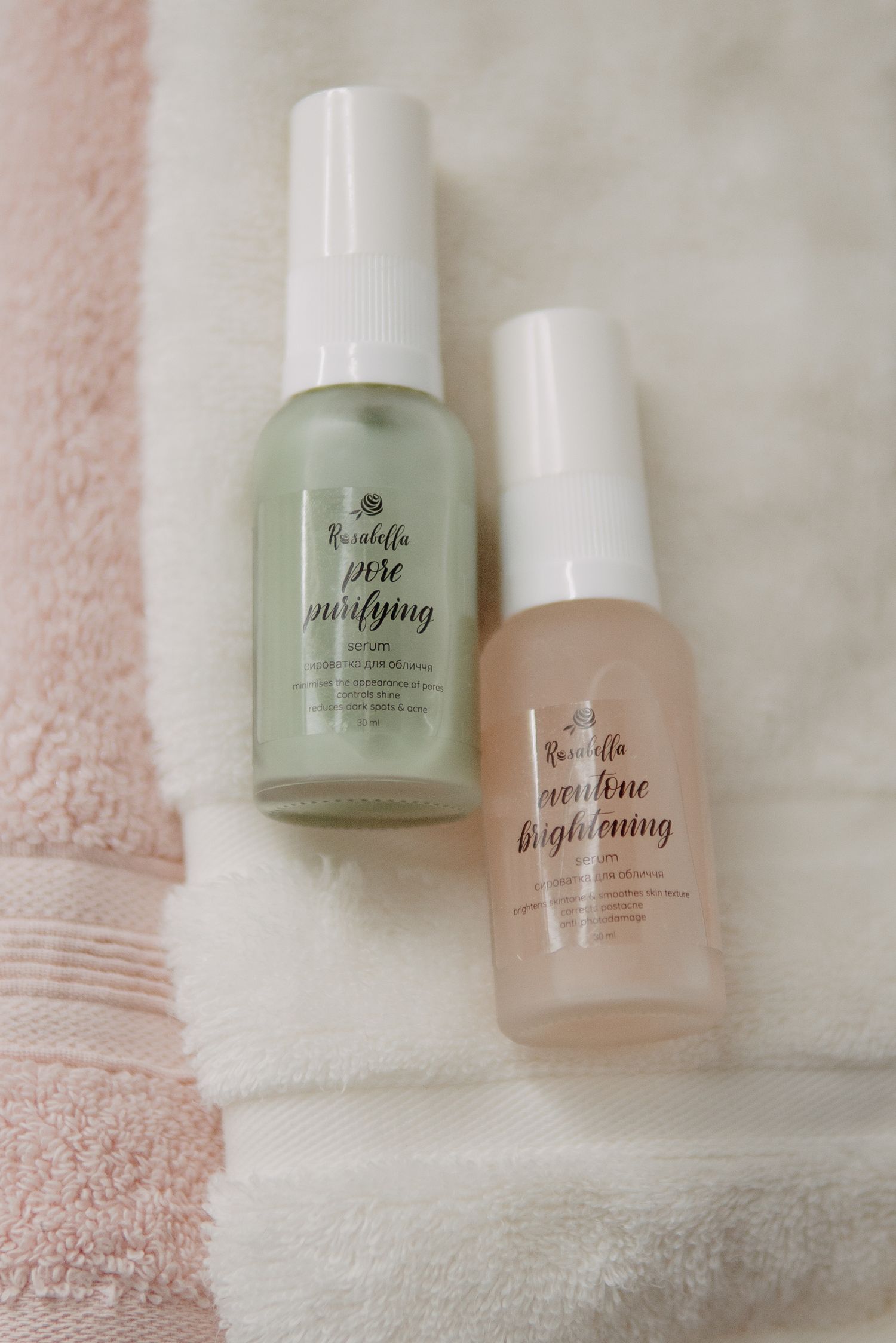 Two Rosalilla skincare serums, pore purifying and brightening, displayed on white fluffy towels.