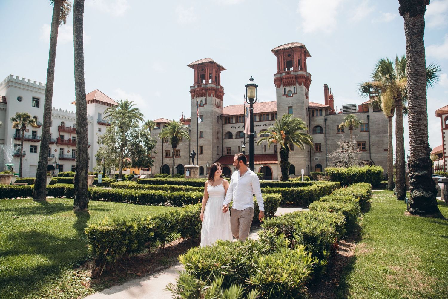 Bride and groom walking through lush garden pathways at the historic Lightner Museum in St. Augustine, Florida.