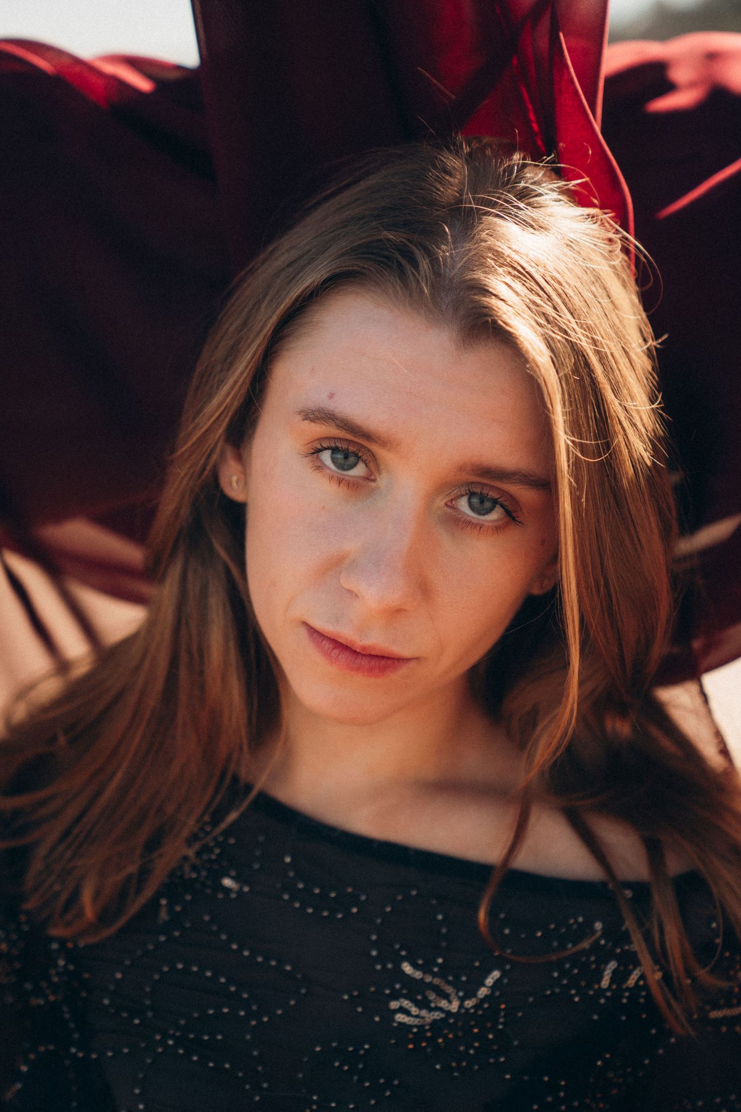 Portrait series in dramatic lighting shows subject with brown hair wearing dark clothing against red background.