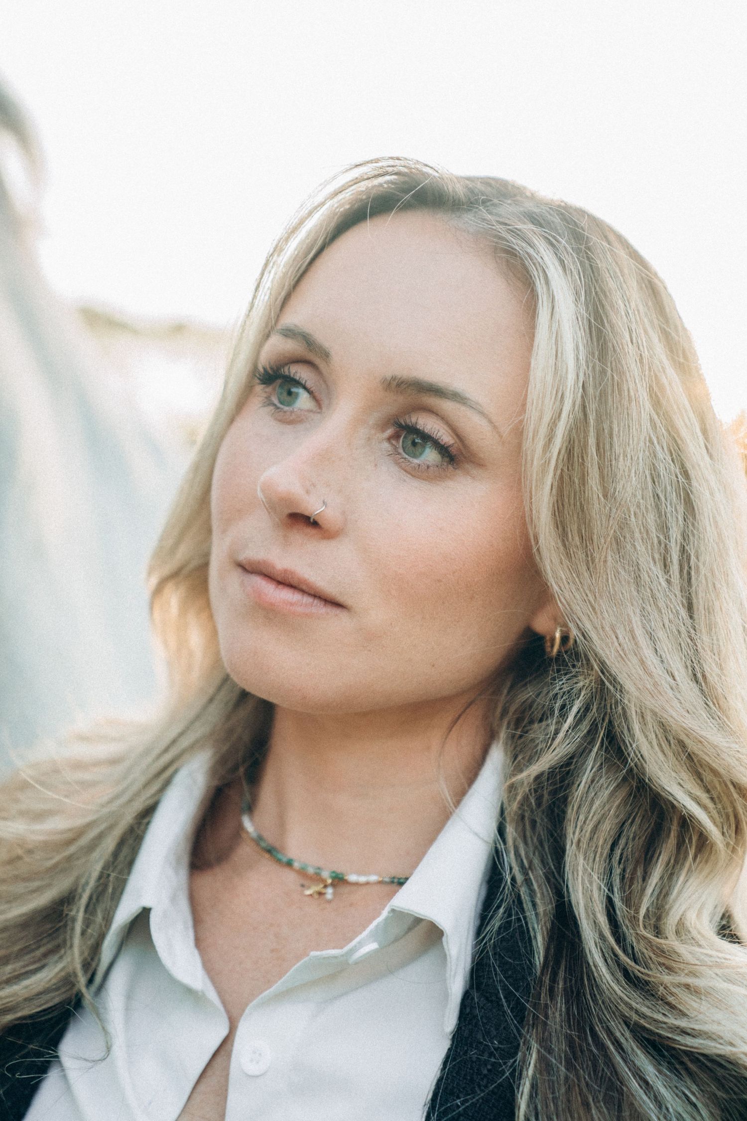Portrait of a woman with blonde hair wearing a white collared shirt and choker necklace.