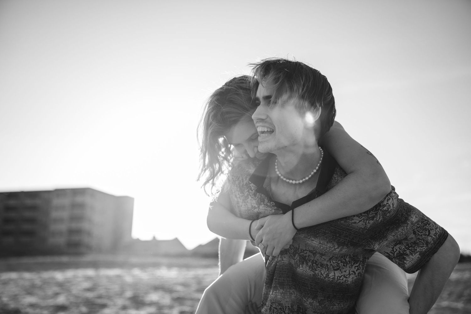 A couple shares tender moments and laughter in black and white portraits.