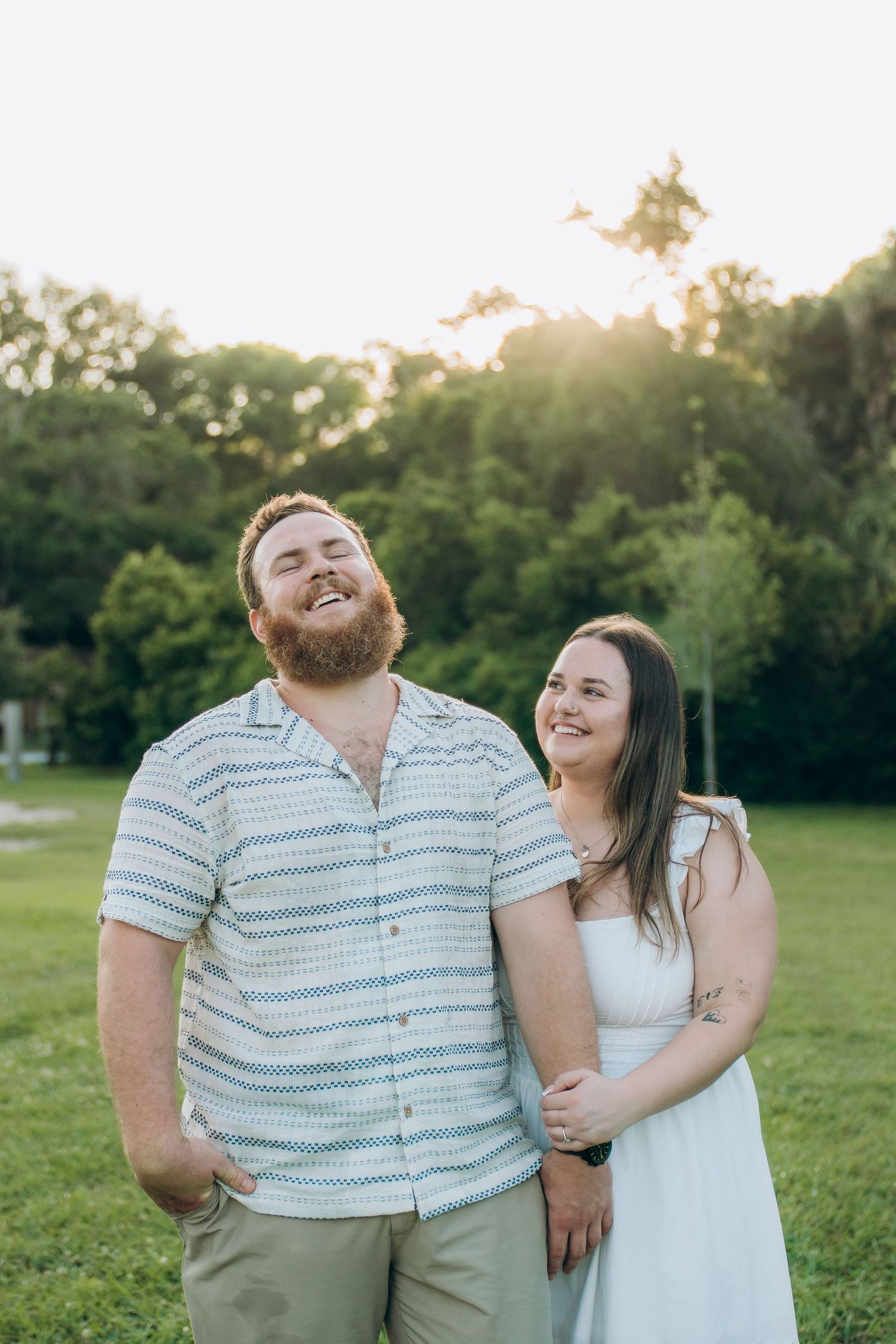Couple in casual attire sharing joyful moments in a sunny green field.
