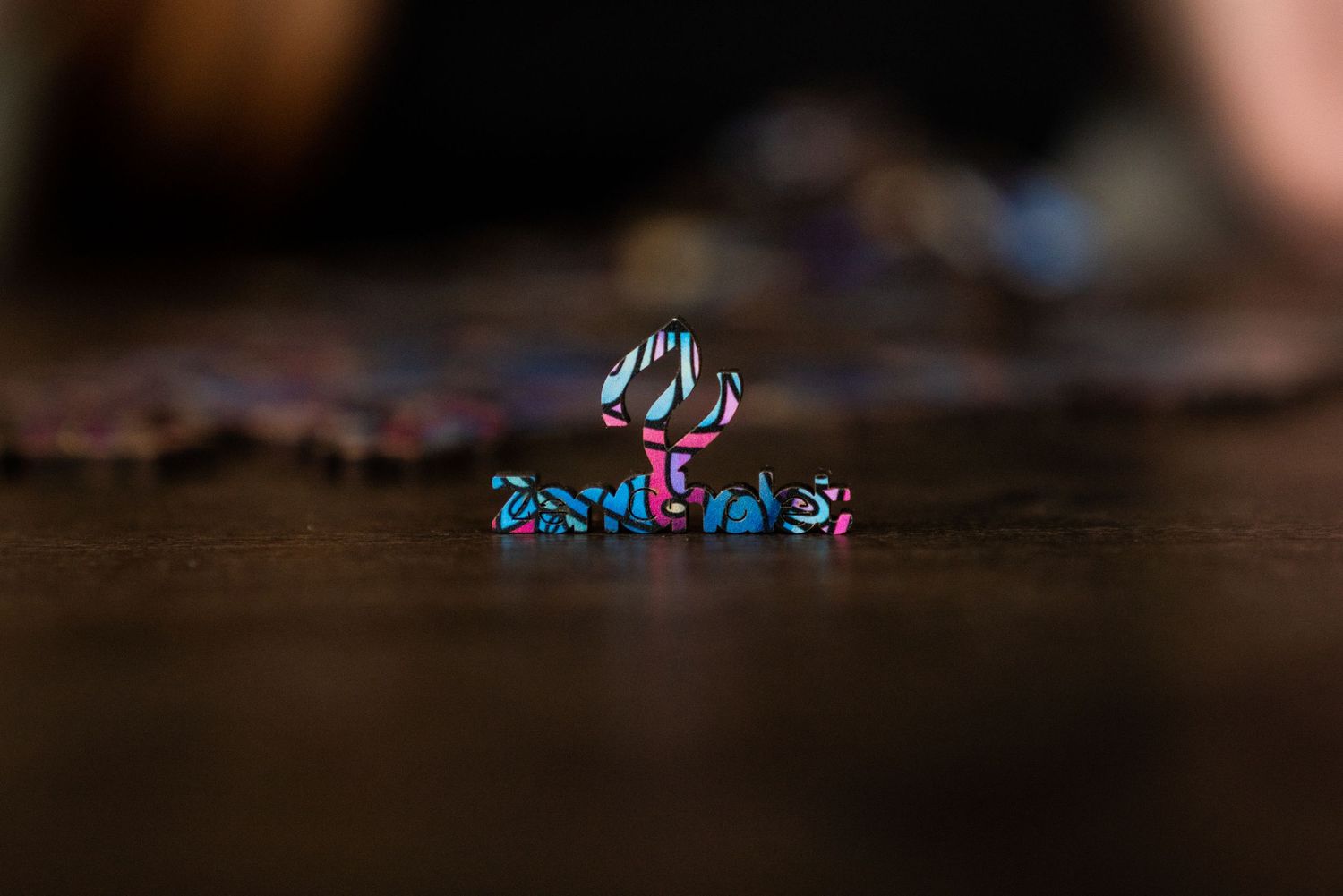 Macro shot of tiny colorful wooden puzzle pieces on a dark wooden surface.