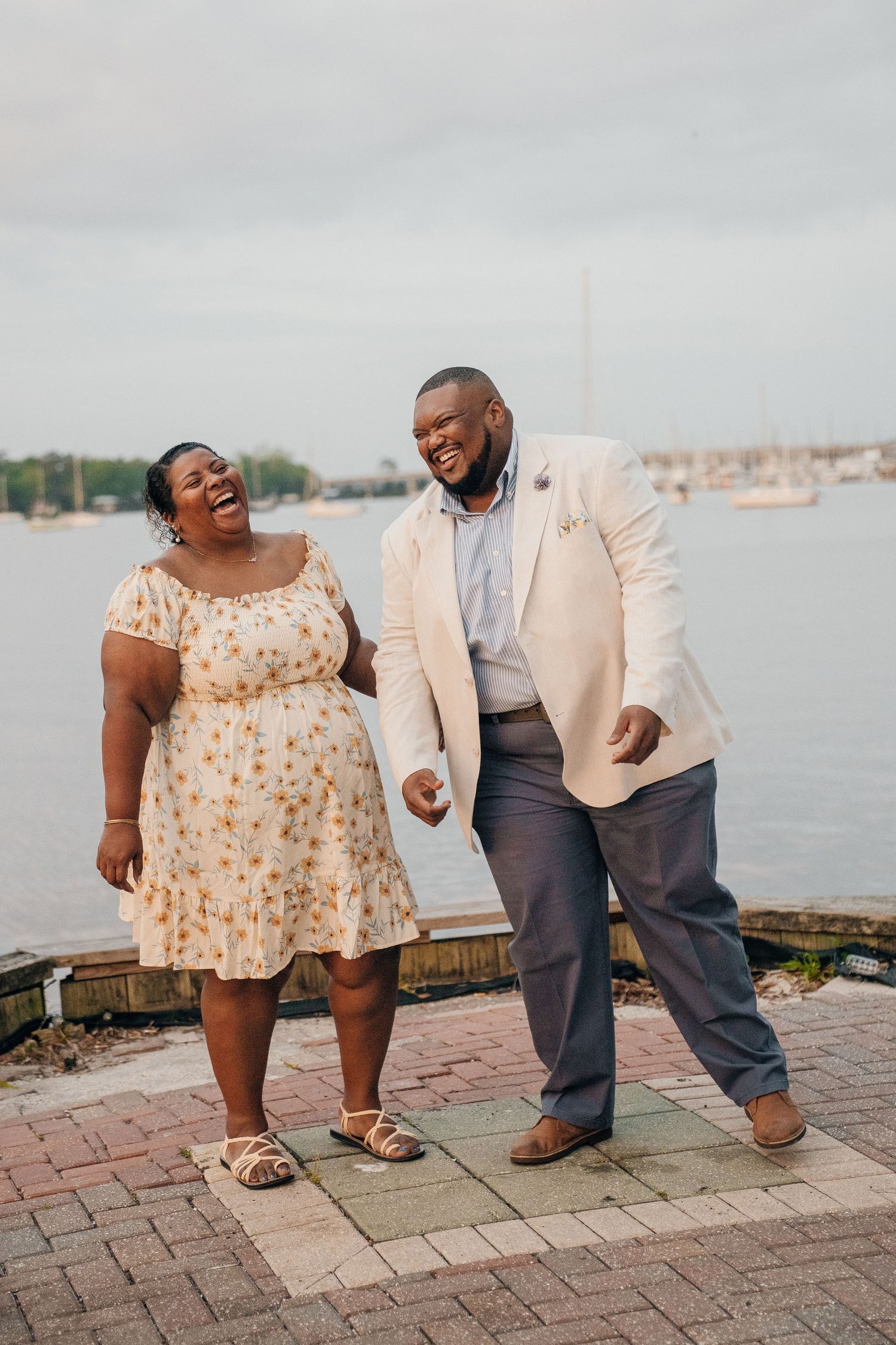 Couple sharing playful moments on a waterfront brick patio.