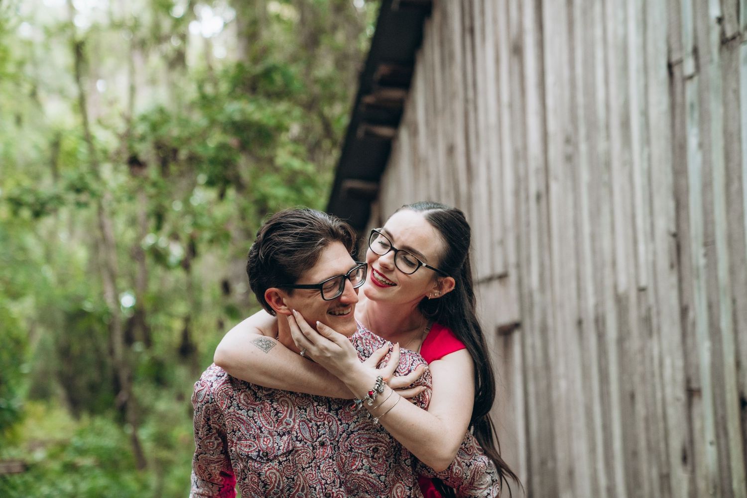 Rustic wooden barn wall provides backdrop for romantic outdoor photoshoot.
