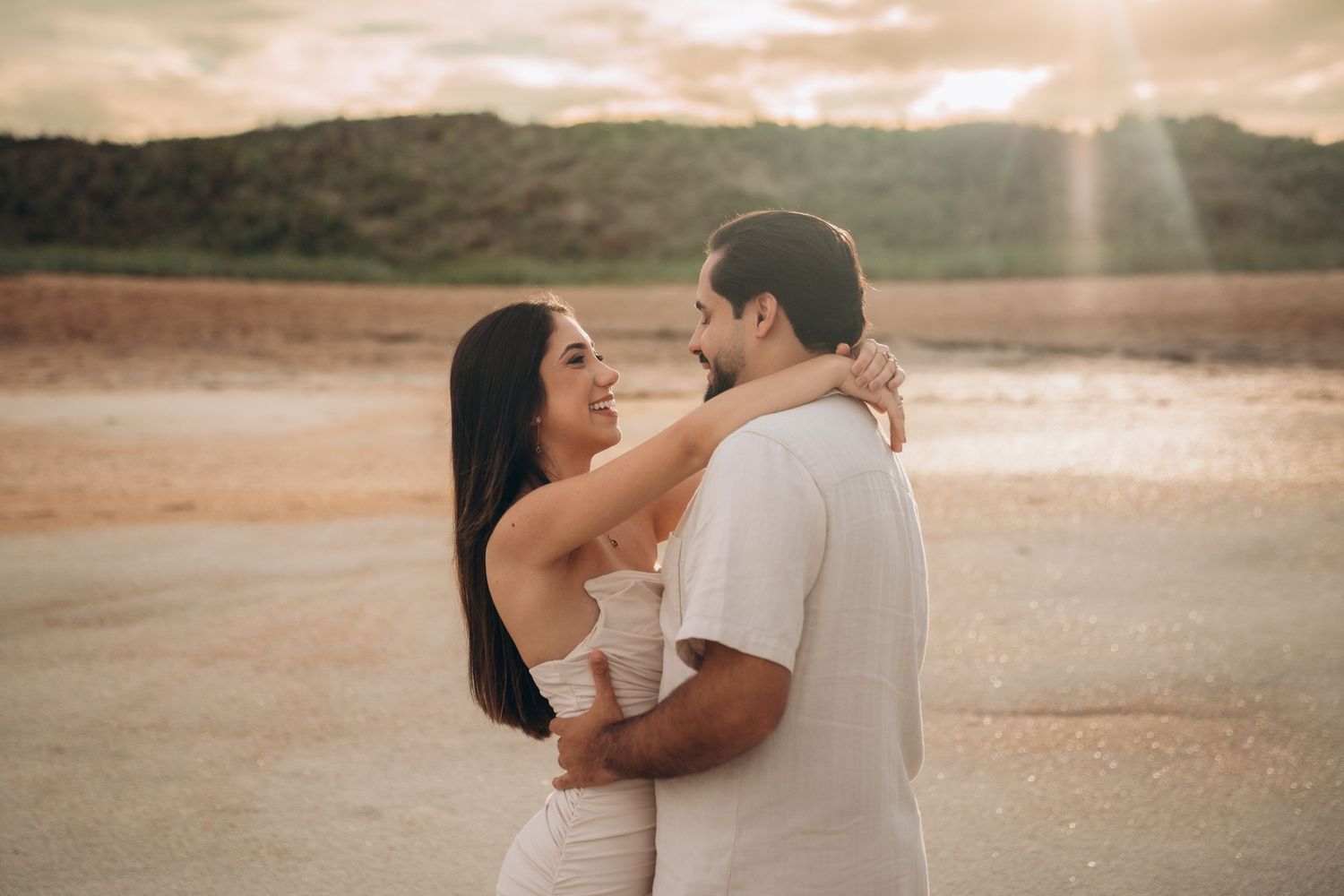 Couple sharing romantic moment on beach during golden sunset.