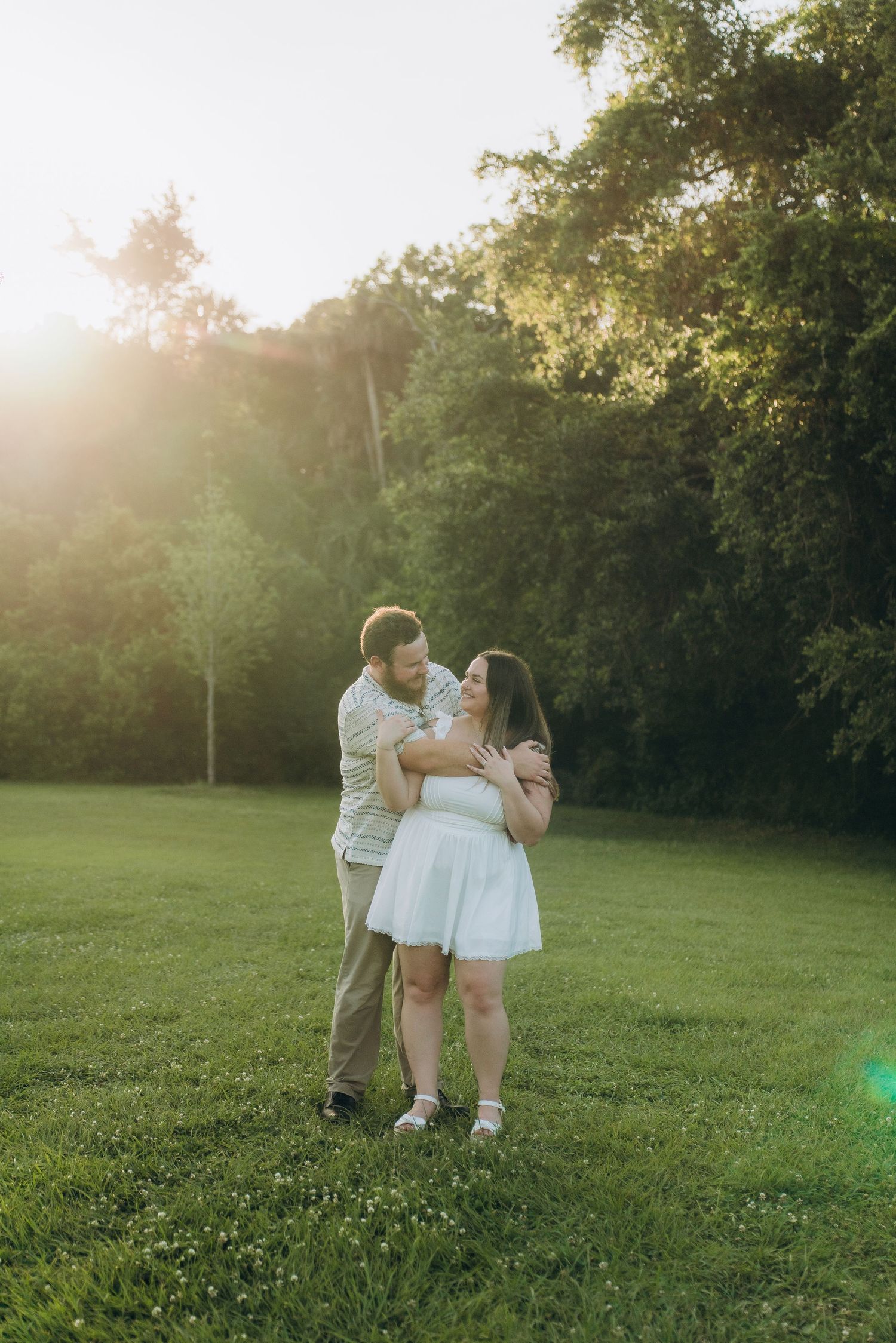 Romantic couple embracing in a sunlit meadow during golden hour.